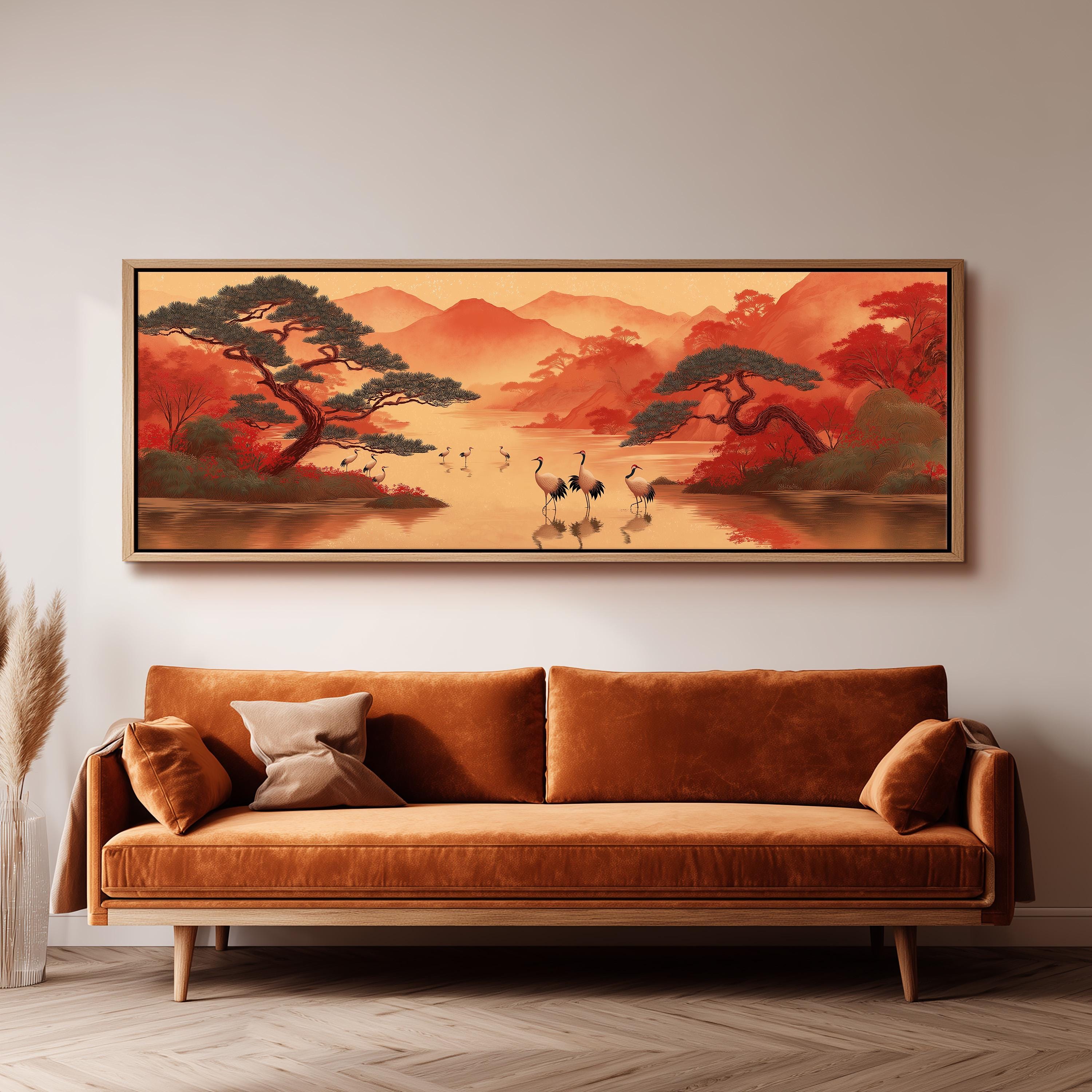 a large, framed painting of a serene landscape with a lake, mountains, and trees, hanging on a wall above a brown sofa.