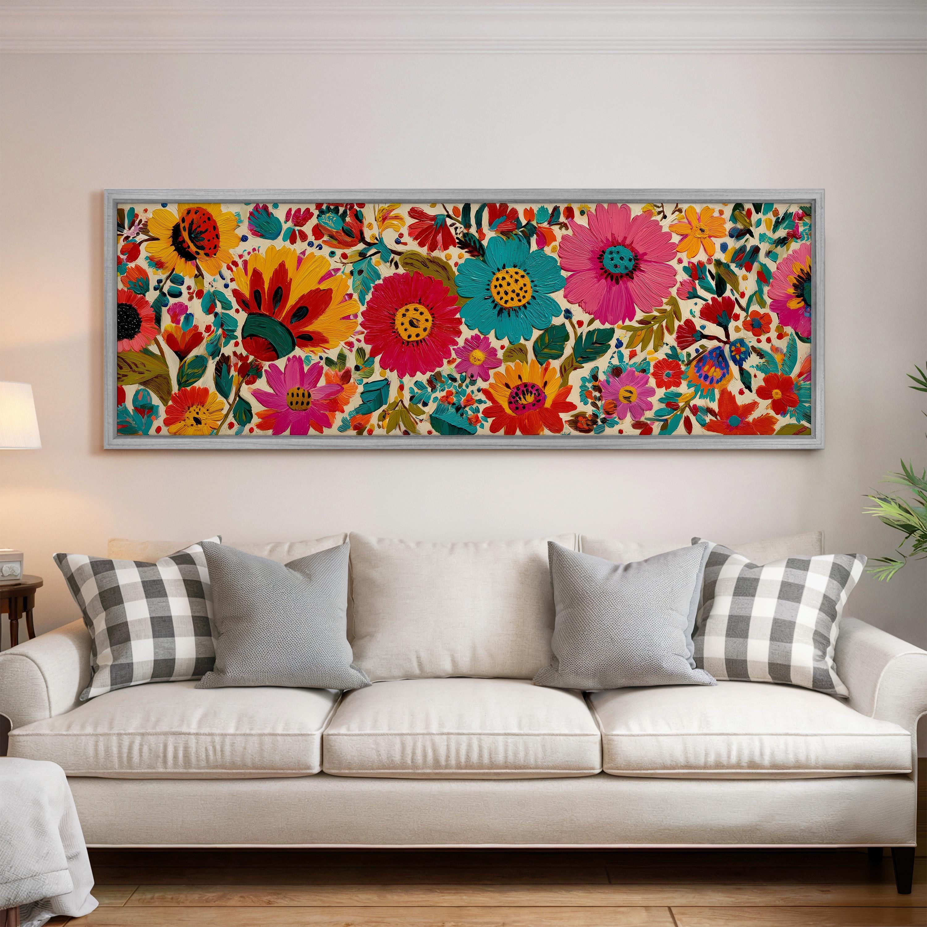 a large, colorful floral print hanging on a wall above a white couch with gray and white plaid throw pillows.