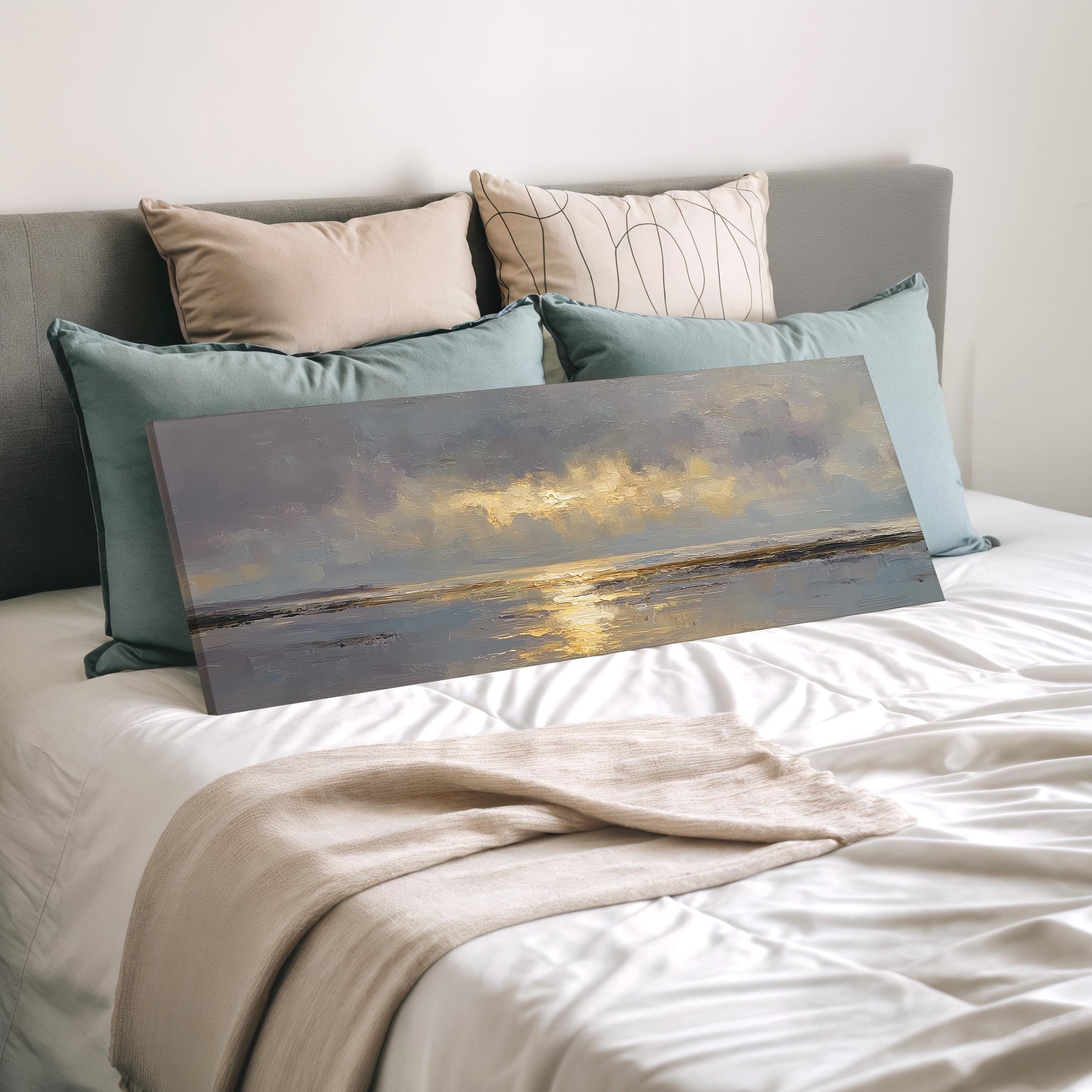 a bedroom with a large painting of a serene landscape resting on a bed, surrounded by various pillows and a white comforter.