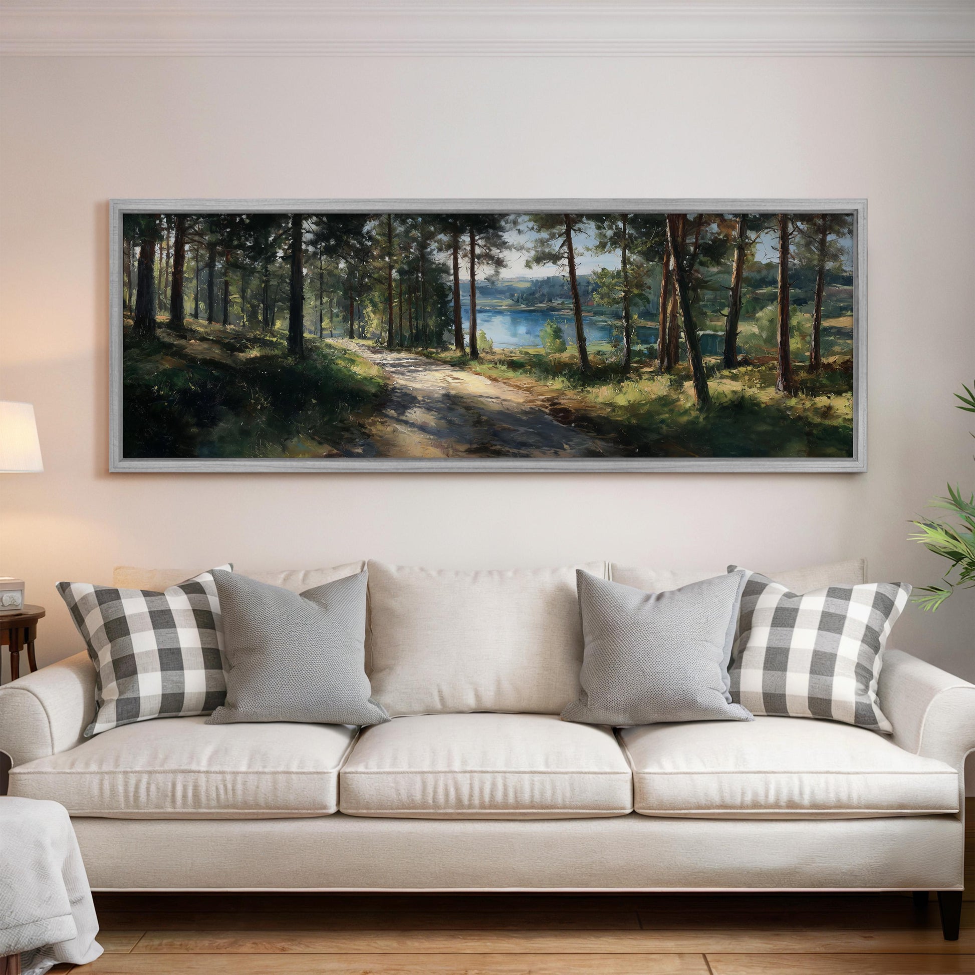 a large painting of a forest scene hanging on a wall above a white sofa with gray and white patterned pillows.