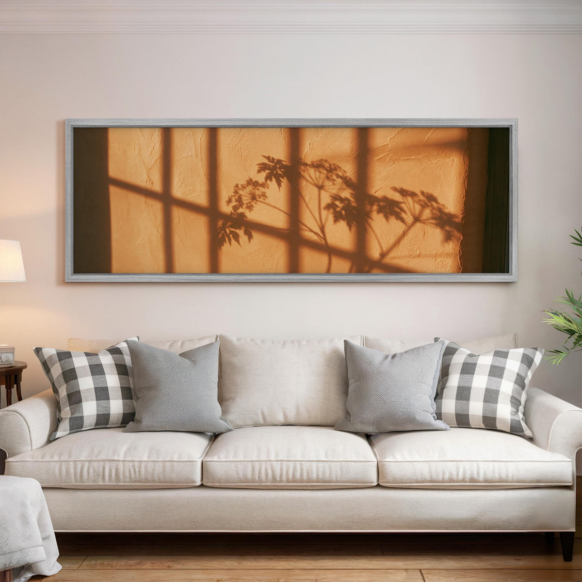Plant and window shadows on a terracotta wall panoramic canvas print above a white sofa in a bright living room