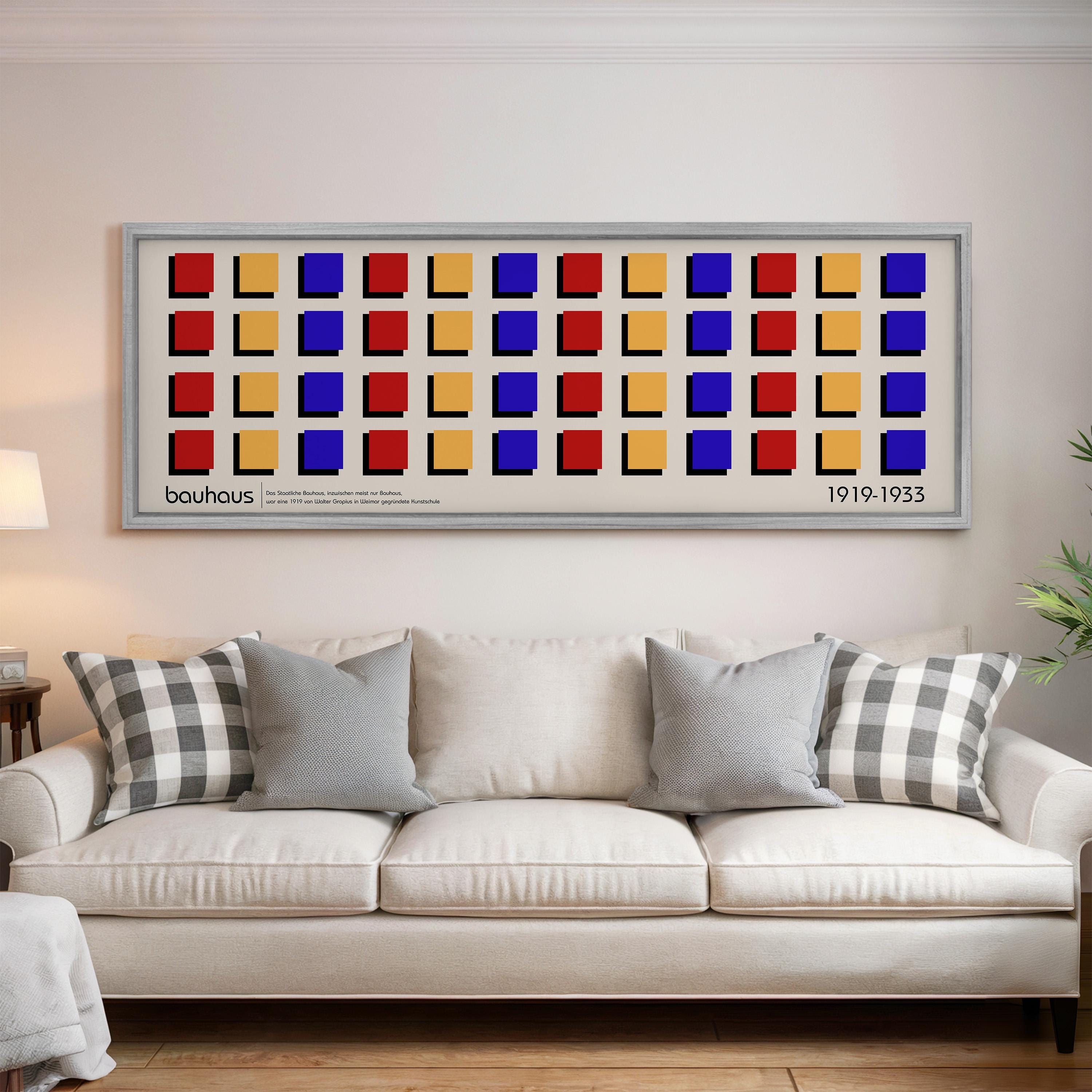 a large framed artwork hanging on a wall above a white couch with gray and black plaid throw pillows.