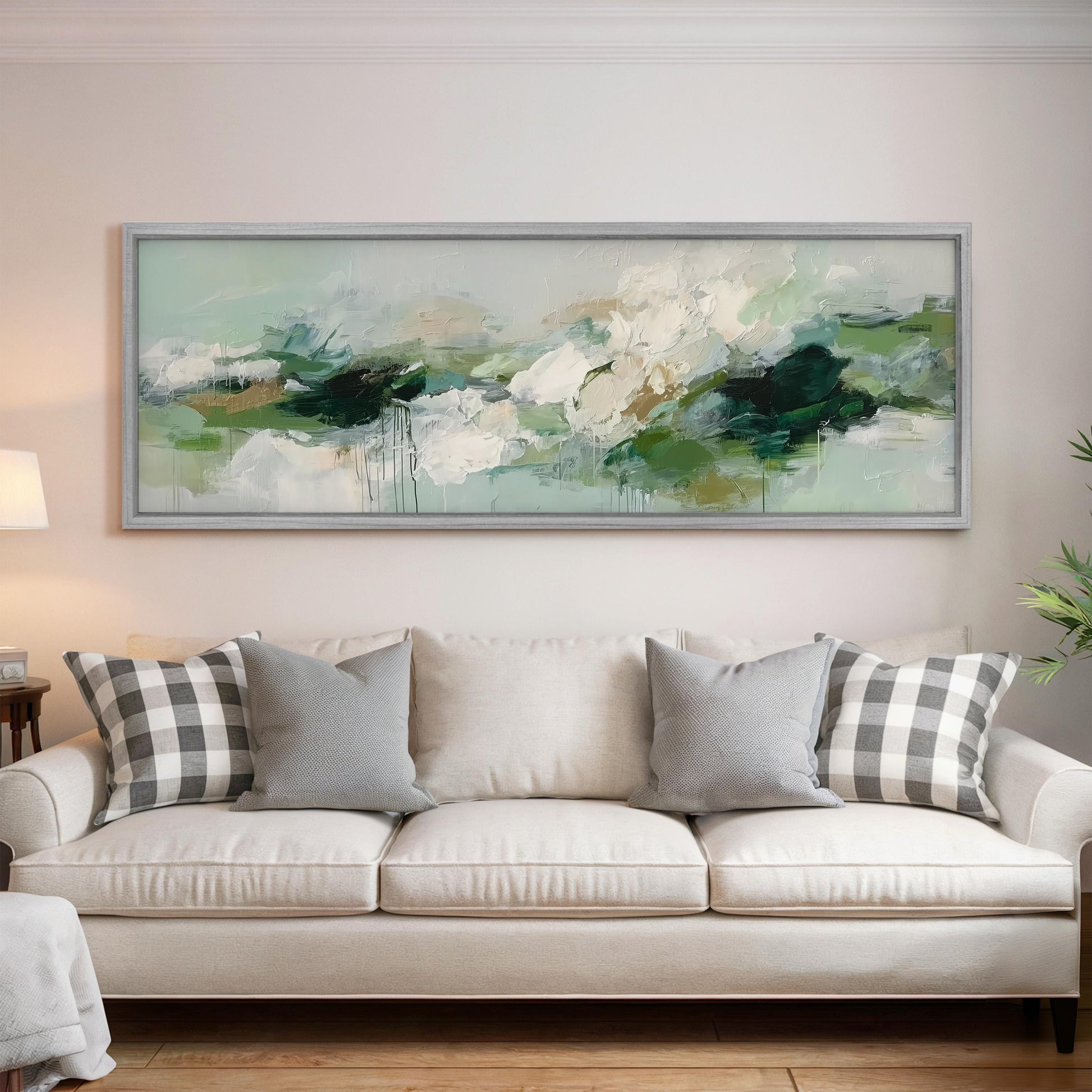 a large, framed painting hanging on a wall above a white sofa with gray and white plaid throw pillows.