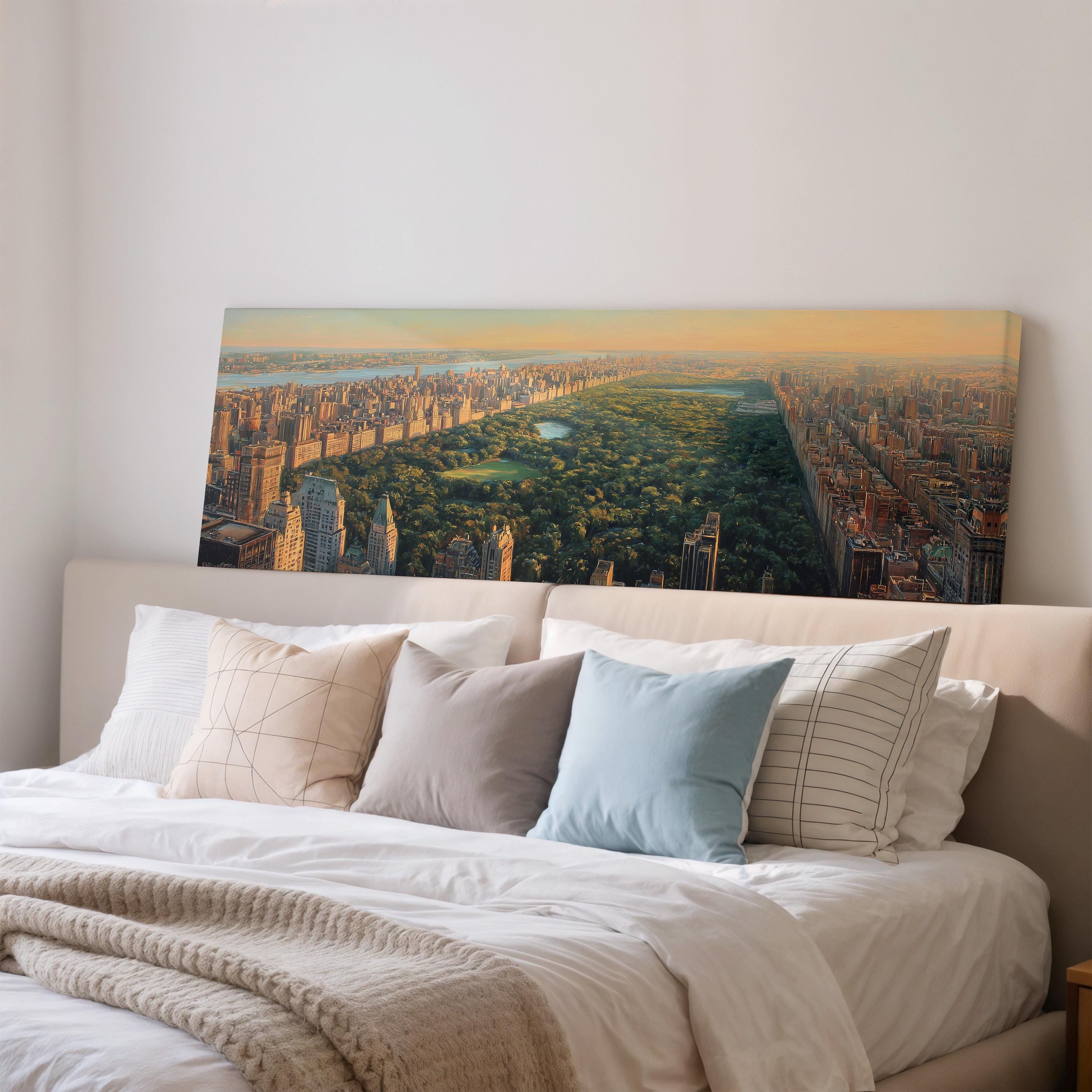 a large, framed painting of a cityscape with a park in the foreground, hanging on a wall above a bed with white bedding and pillows.