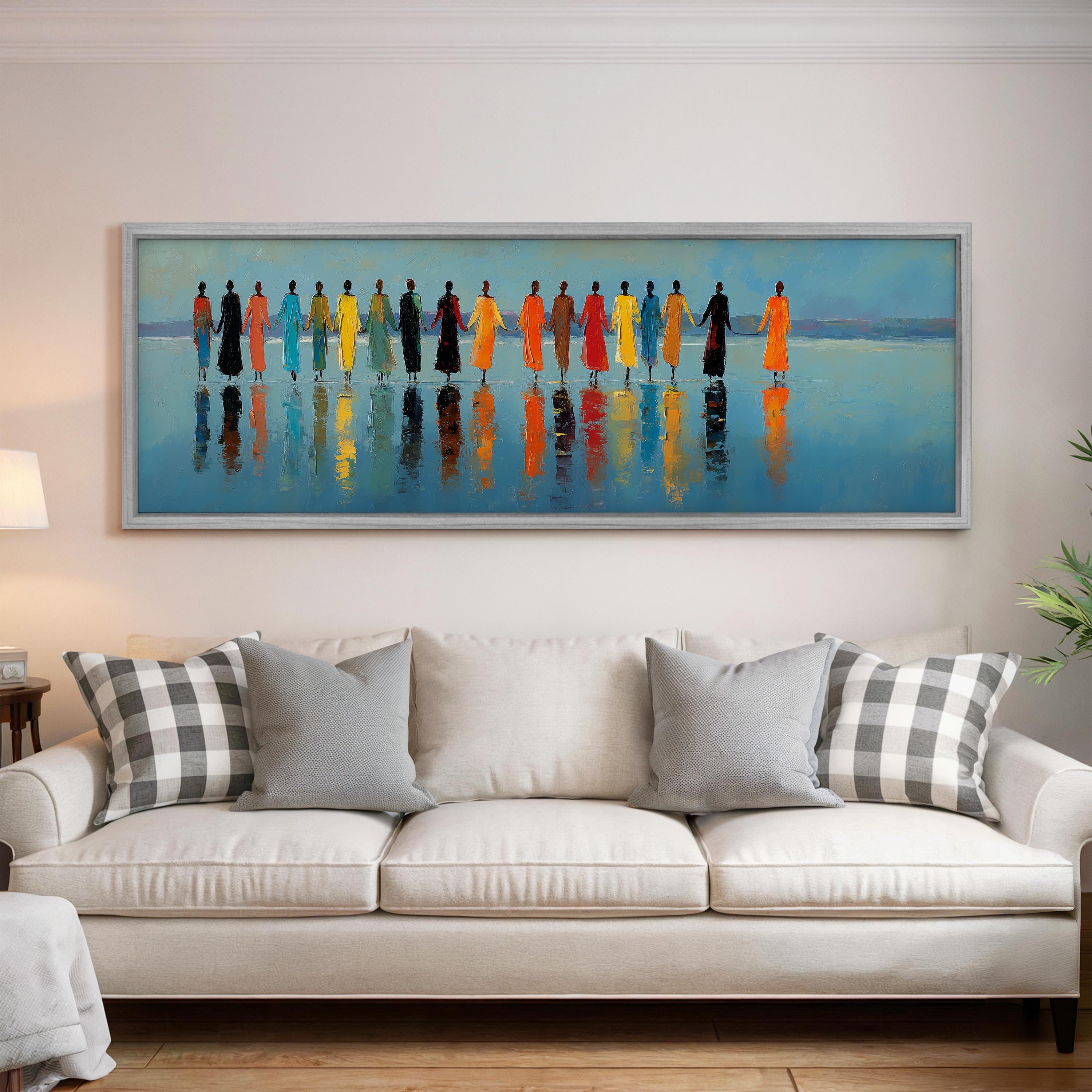 a large painting of a group of people standing in a line, with their reflections visible in the water below. The painting is hung on a wall above a white couch with gray and white patterned pillows.