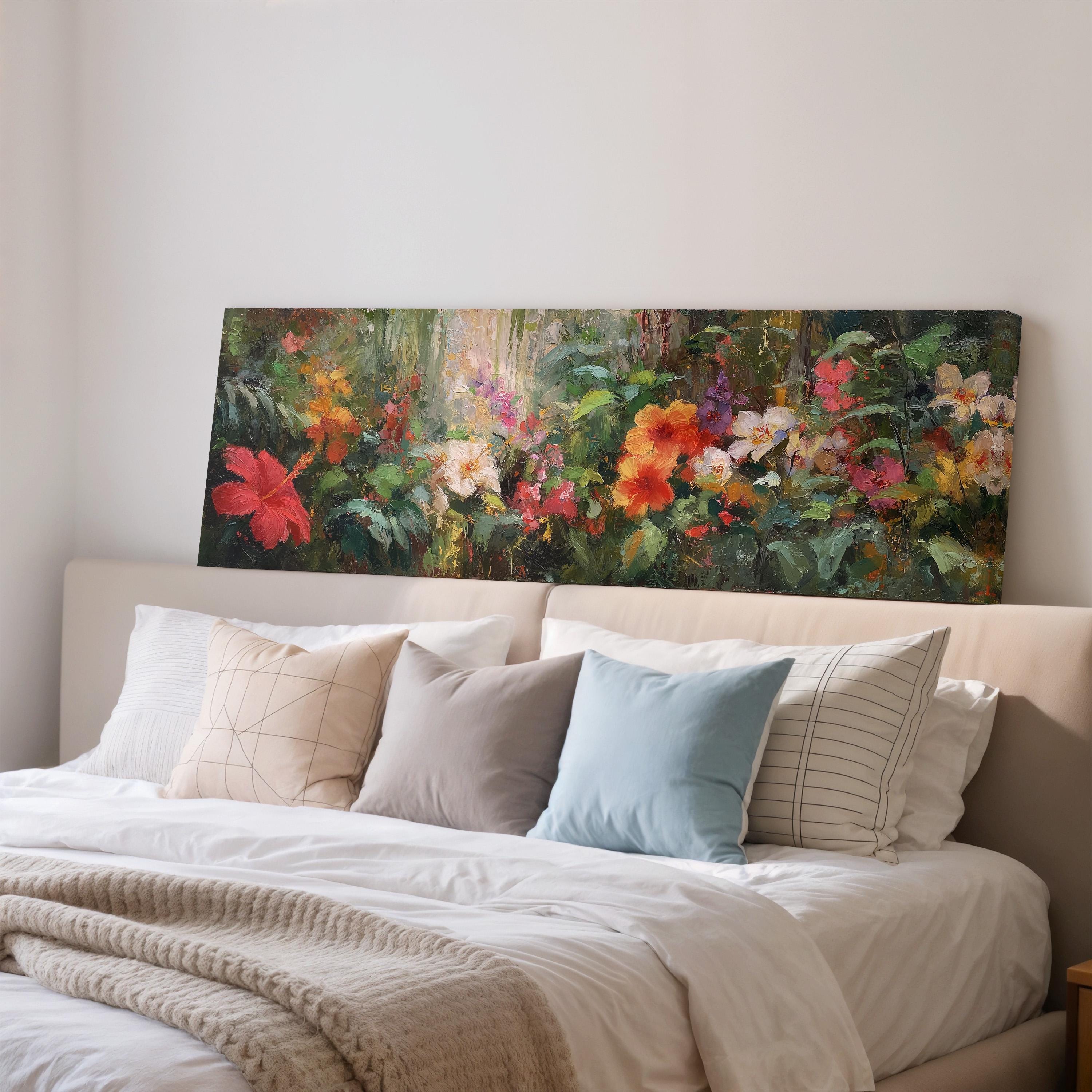 a large painting of a colorful garden scene hanging on a wall above a bed with white pillows and a gray blanket.