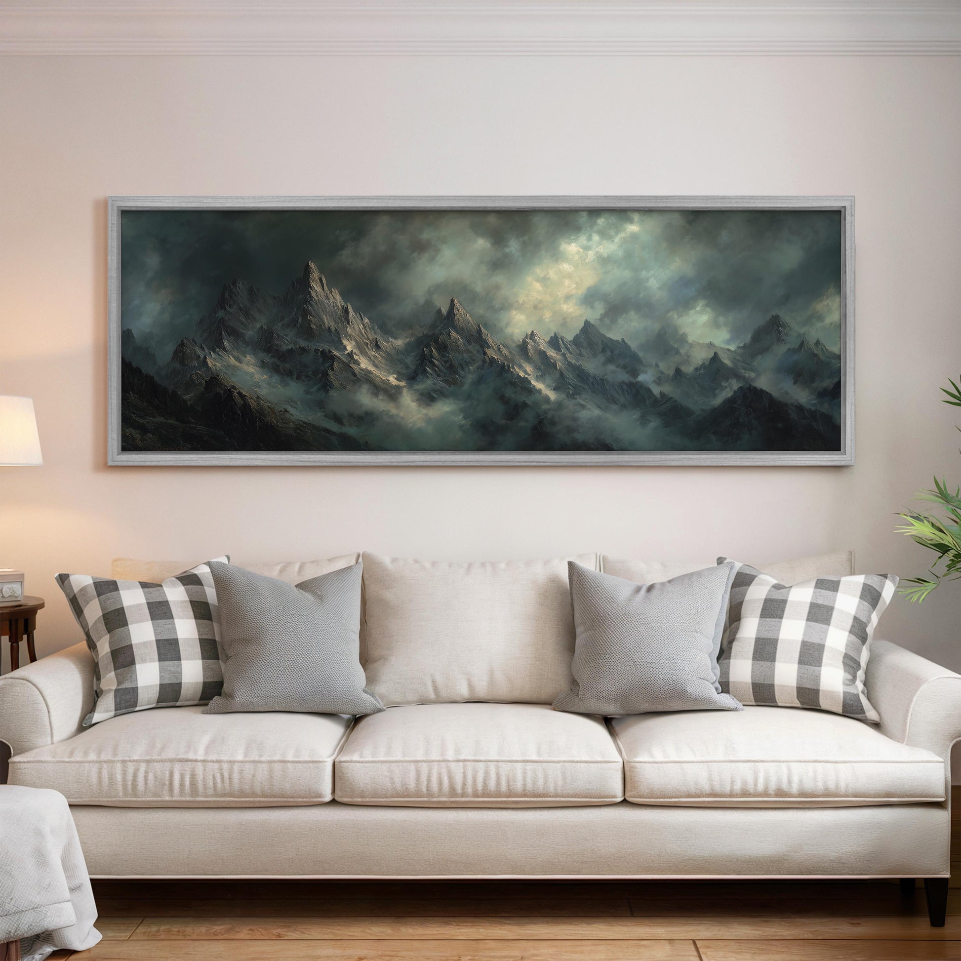 a large, framed painting of a mountainous landscape hanging on a wall above a white sofa with gray and white plaid throw pillows.