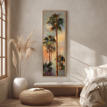 a large painting of palm trees hanging on a wall in a room with a bed, a wicker ottoman, and a potted plant.