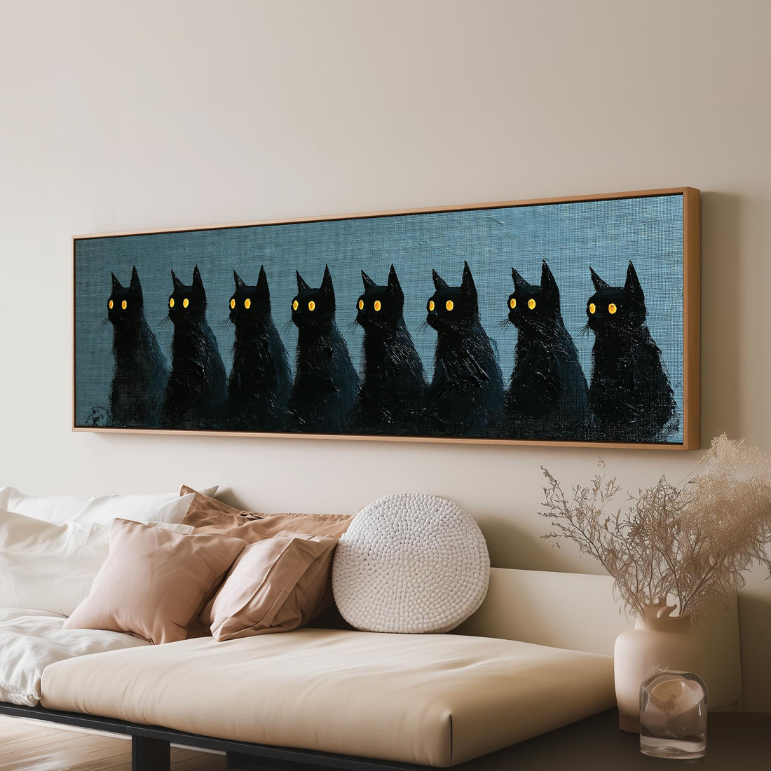 Row of black cats with glowing eyes long horizontal canvas print above a sofa in a living room