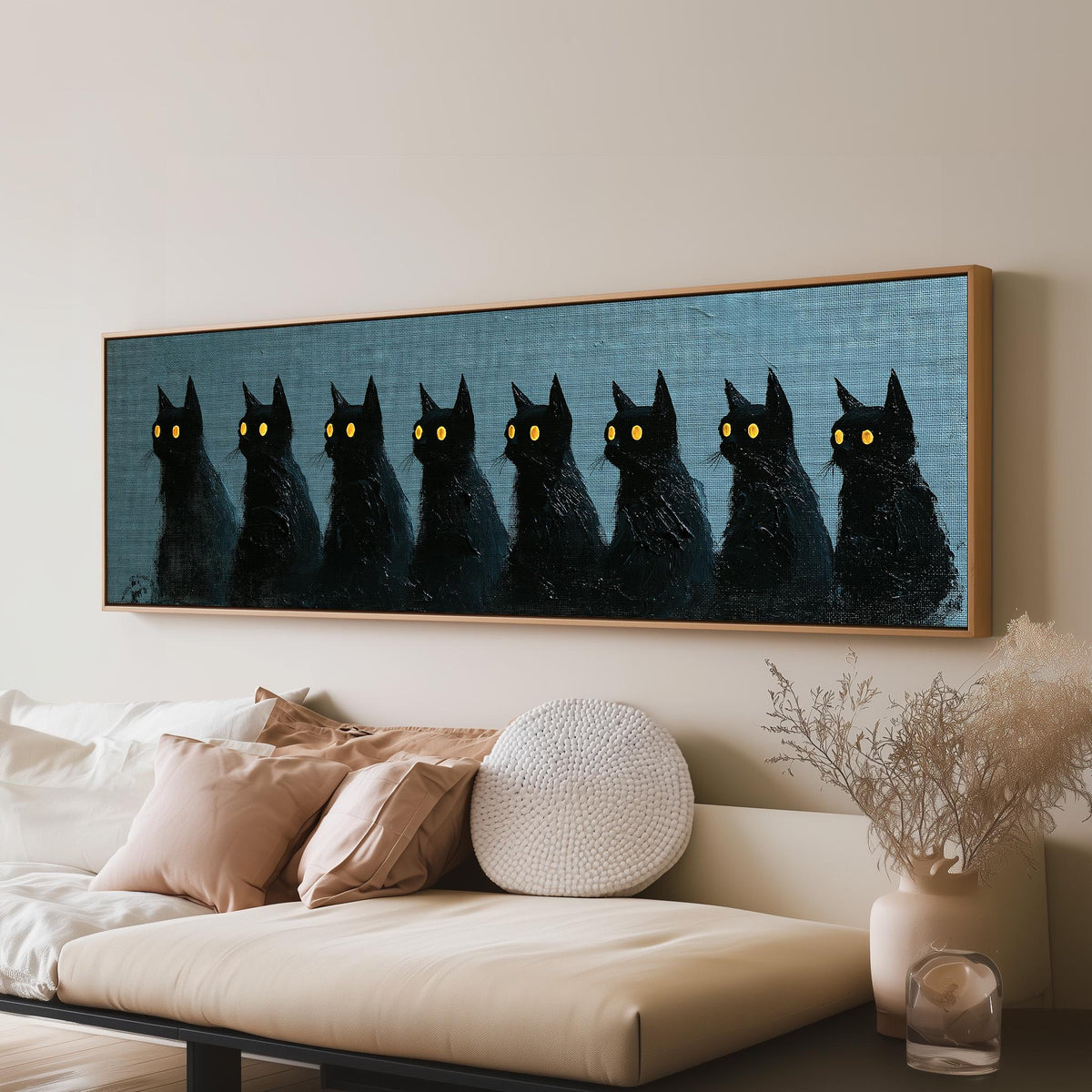 Row of black cats with glowing eyes long horizontal canvas print above a sofa in a living room
