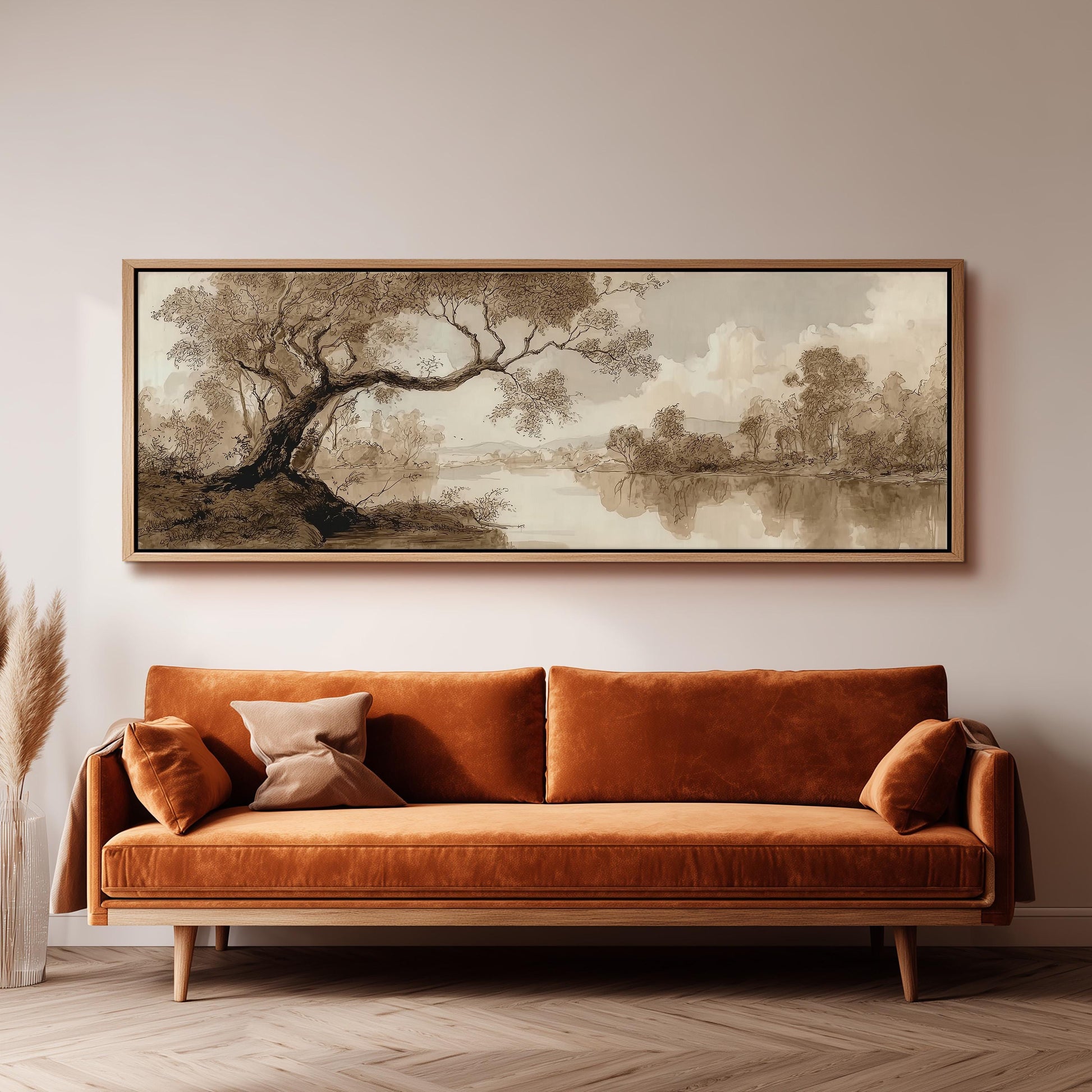 a large, framed painting of a landscape hanging on a wall above a brown sofa with orange cushions.