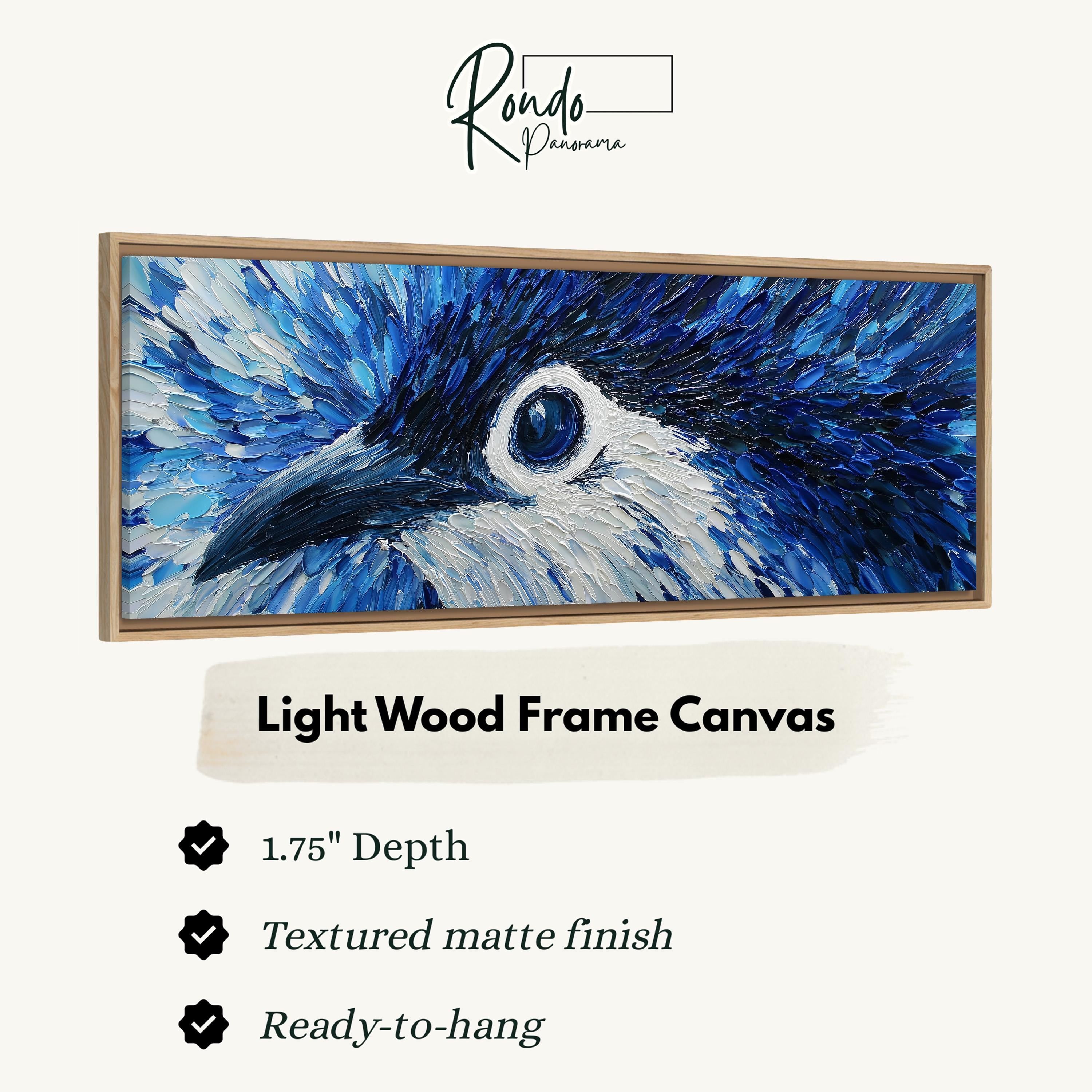 The image is a close-up of a blue bird's eye, with a light wood frame canvas hanging on a wall.