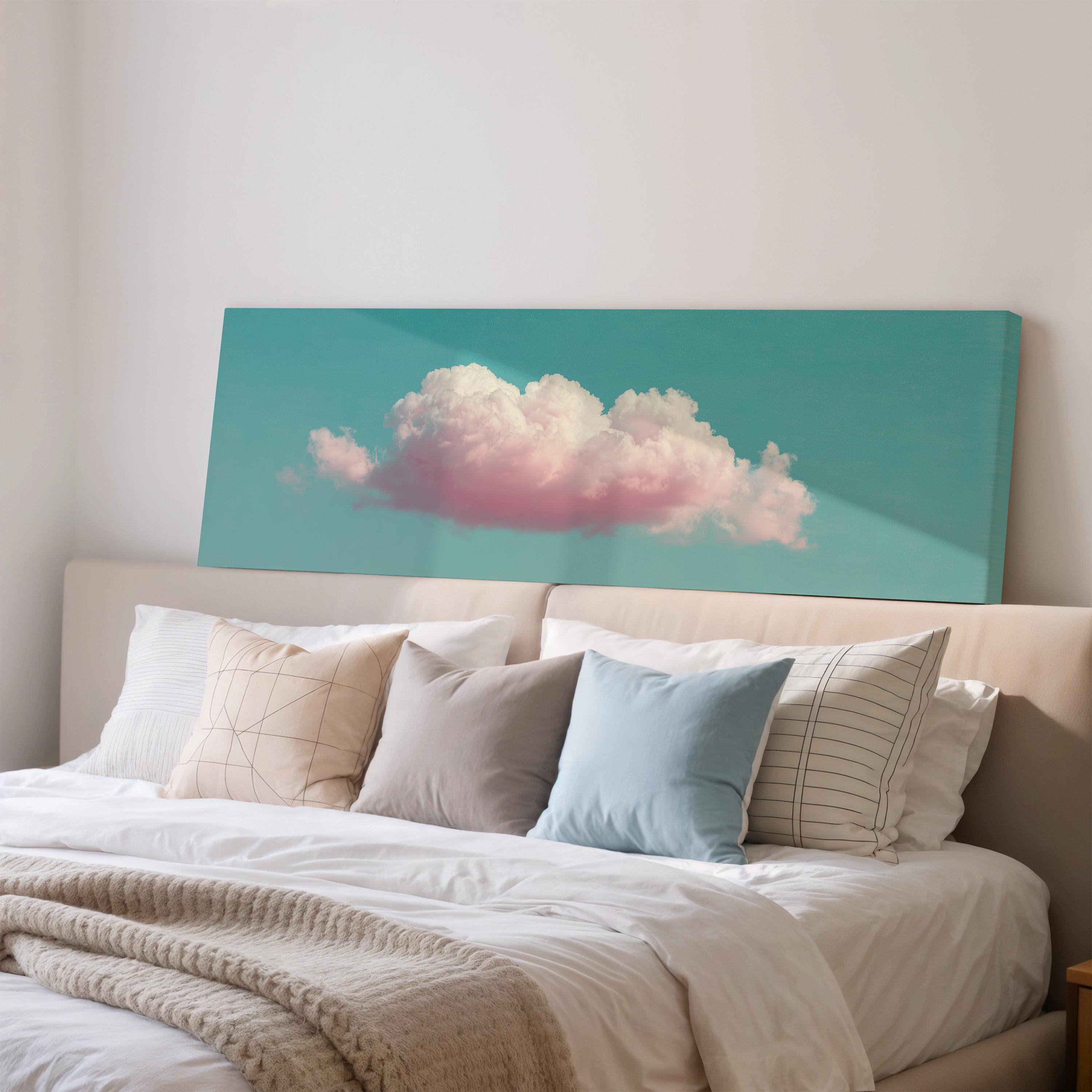 a large bed with white sheets and pillows, and a large canvas print of a cloud painted in pink and white colors is displayed above the bed.