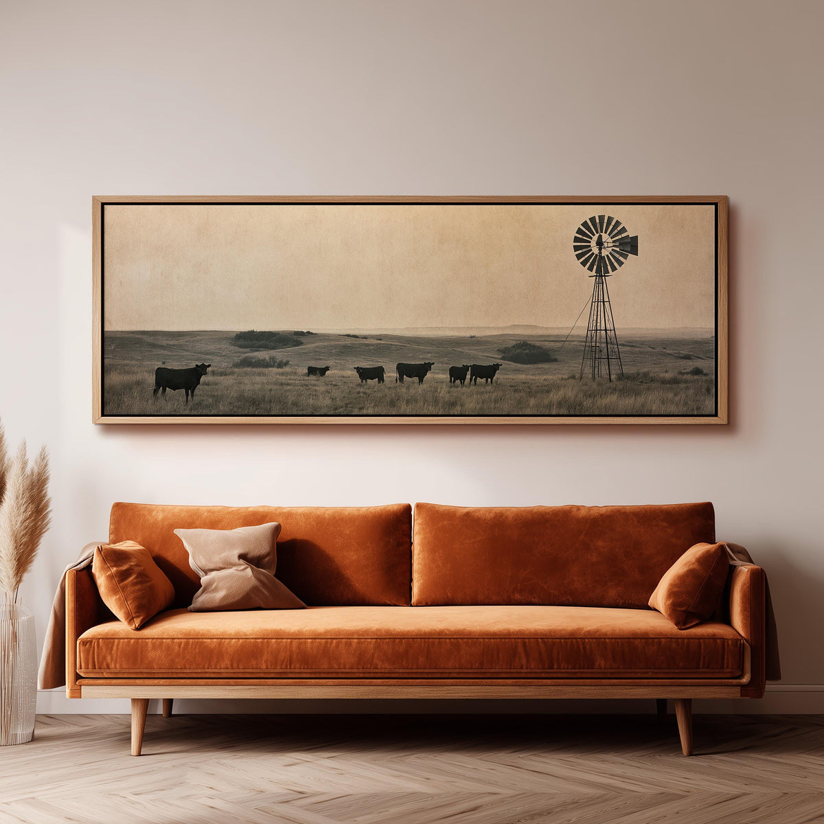 Black cattle grazing by a windmill on the prairie panoramic canvas print above a sofa in a living room