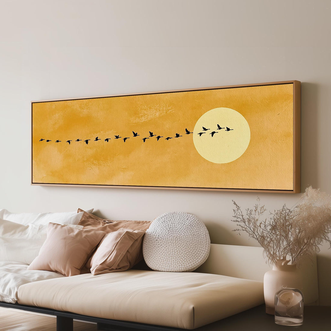 Geese flying toward a pale sun on mustard long horizontal canvas print above a sofa in a living room