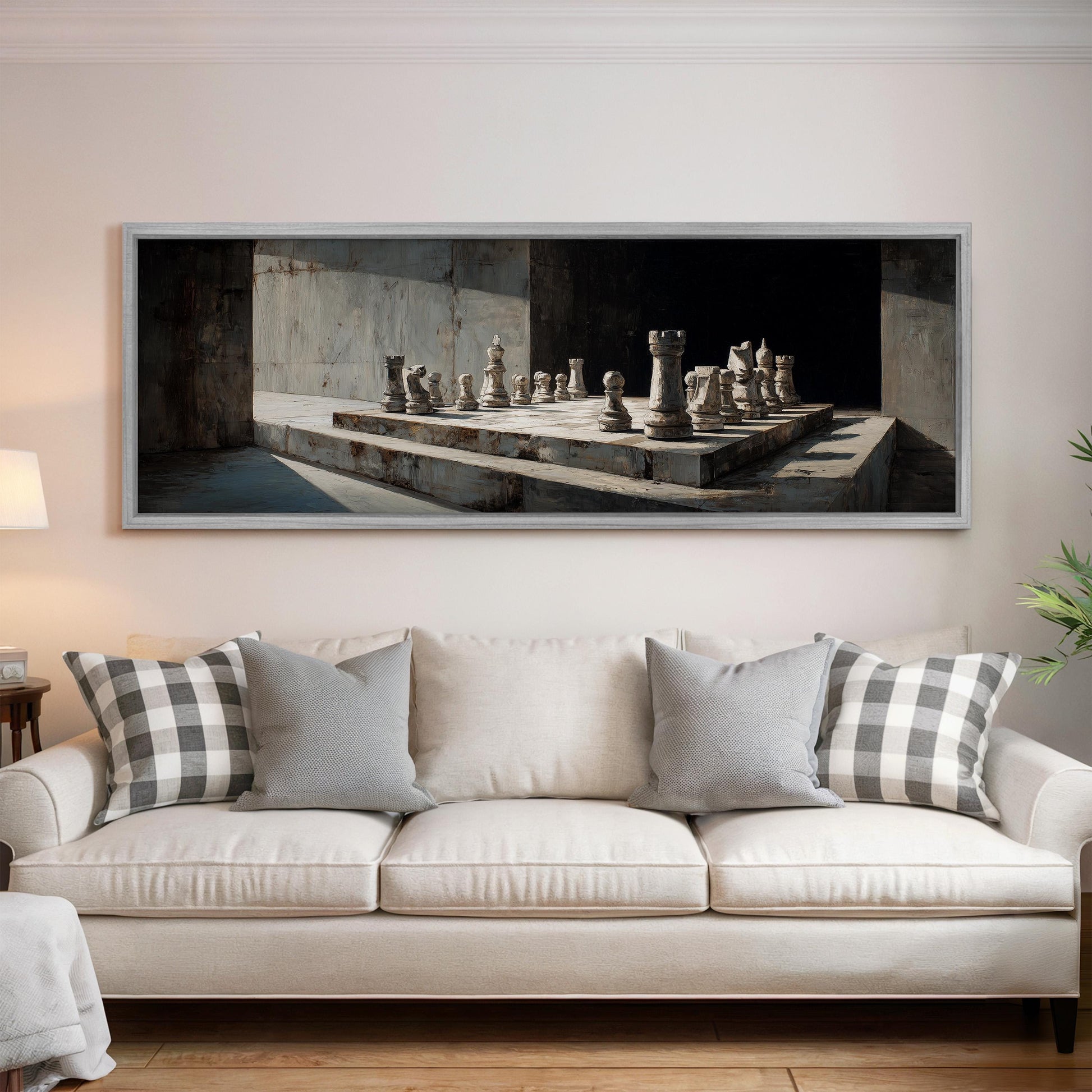 a large framed painting of a chessboard with chess pieces on a white wall above a white sofa with gray and white pillows.