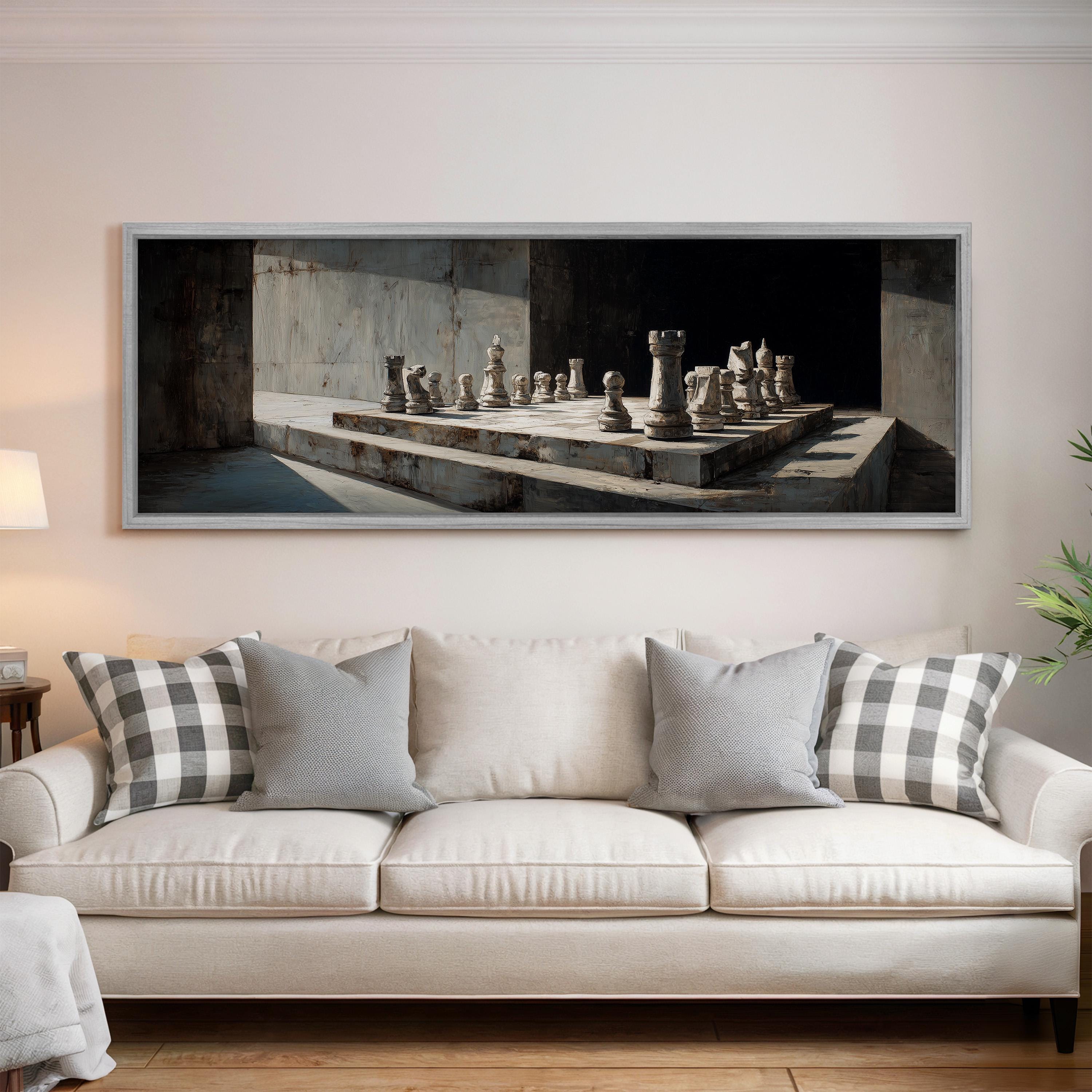 a large framed painting of a chessboard with chess pieces on a white wall above a white sofa with gray and white pillows.