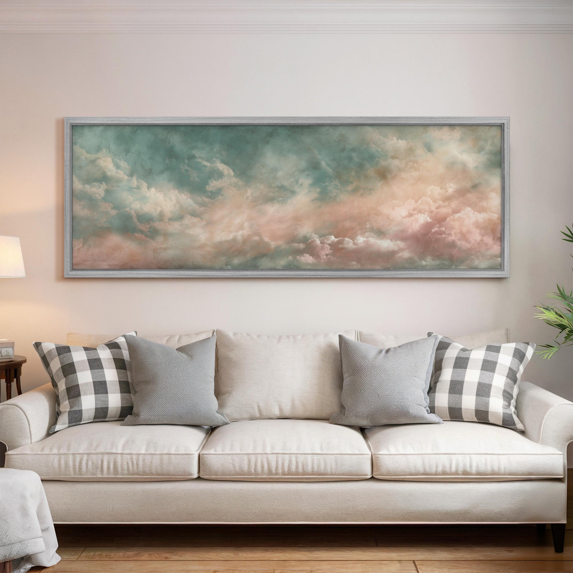a large, framed painting of a cloudy sky hanging above a white couch with gray and black plaid throw pillows.