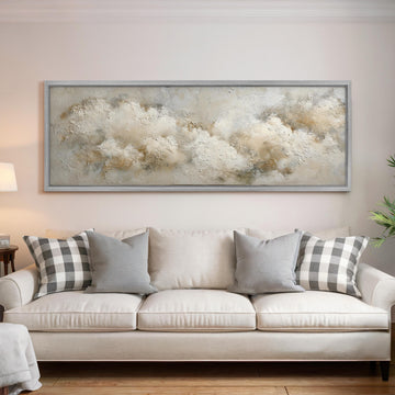 a living room with a large, framed painting of clouds hanging above a white sofa with gray and white plaid throw pillows.