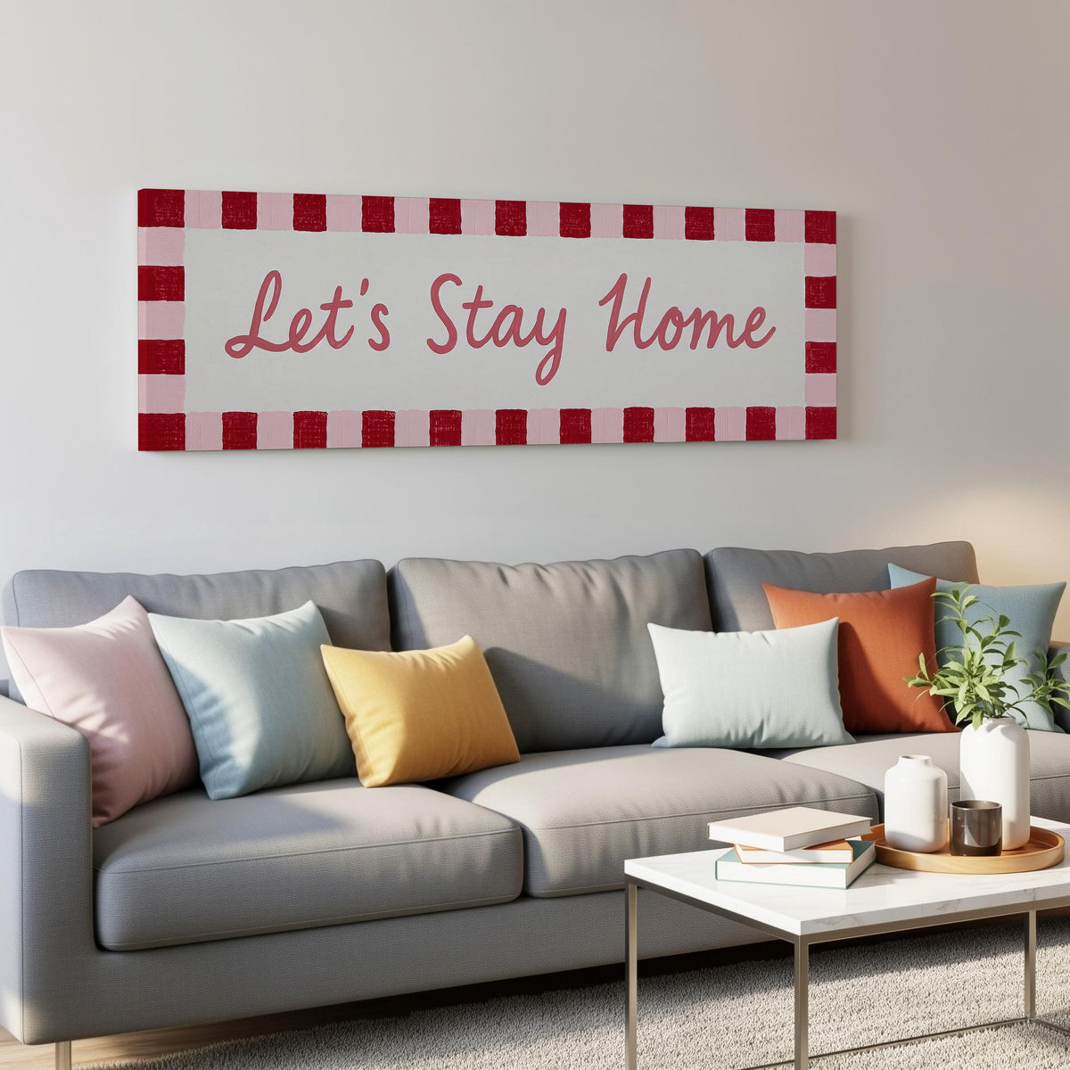 Let's stay home sign with a red checked border panoramic canvas print above a grey sofa in a living room