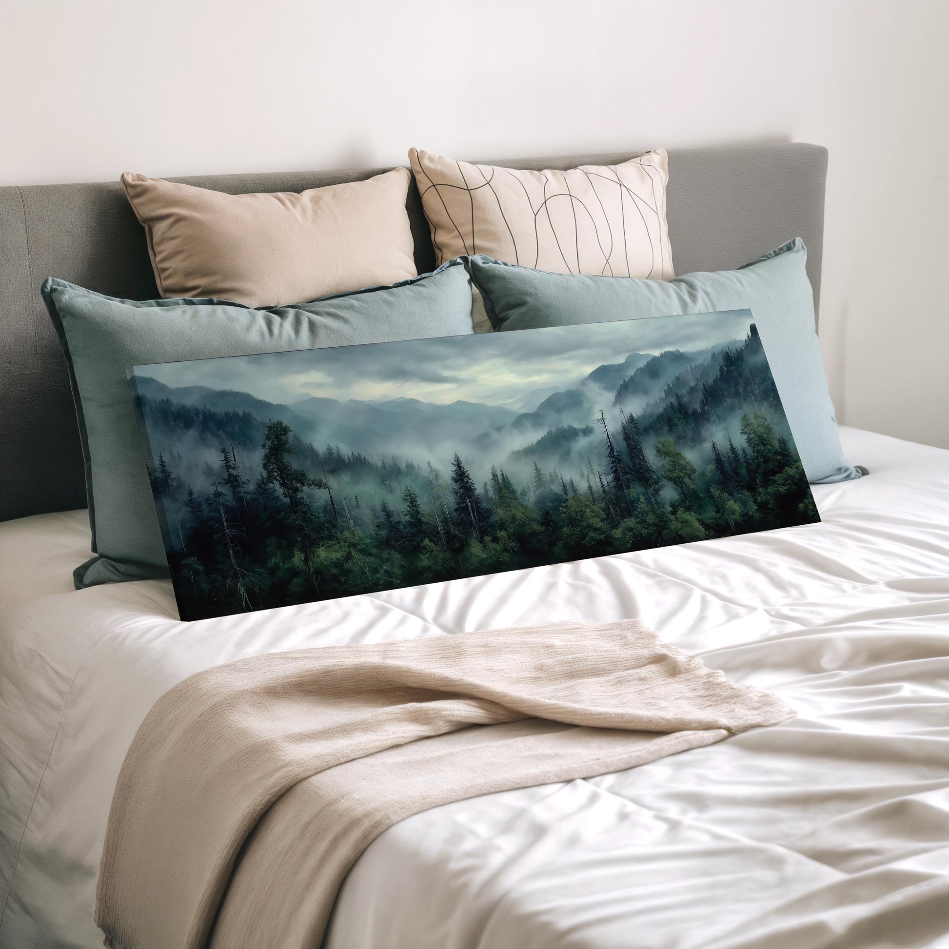 a large landscape painting of a forest scene, with a misty mountain backdrop, displayed on a bed with a white comforter and pillows.