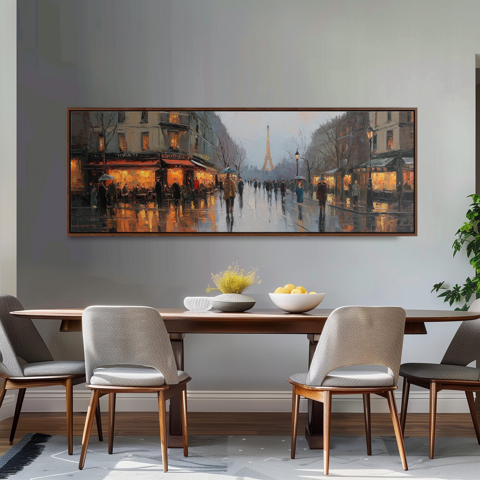 a large painting of a city street scene hanging on a wall above a wooden dining table with four chairs. The painting depicts a rainy day with people walking on the wet street, illuminated by the warm glow of street lamps.