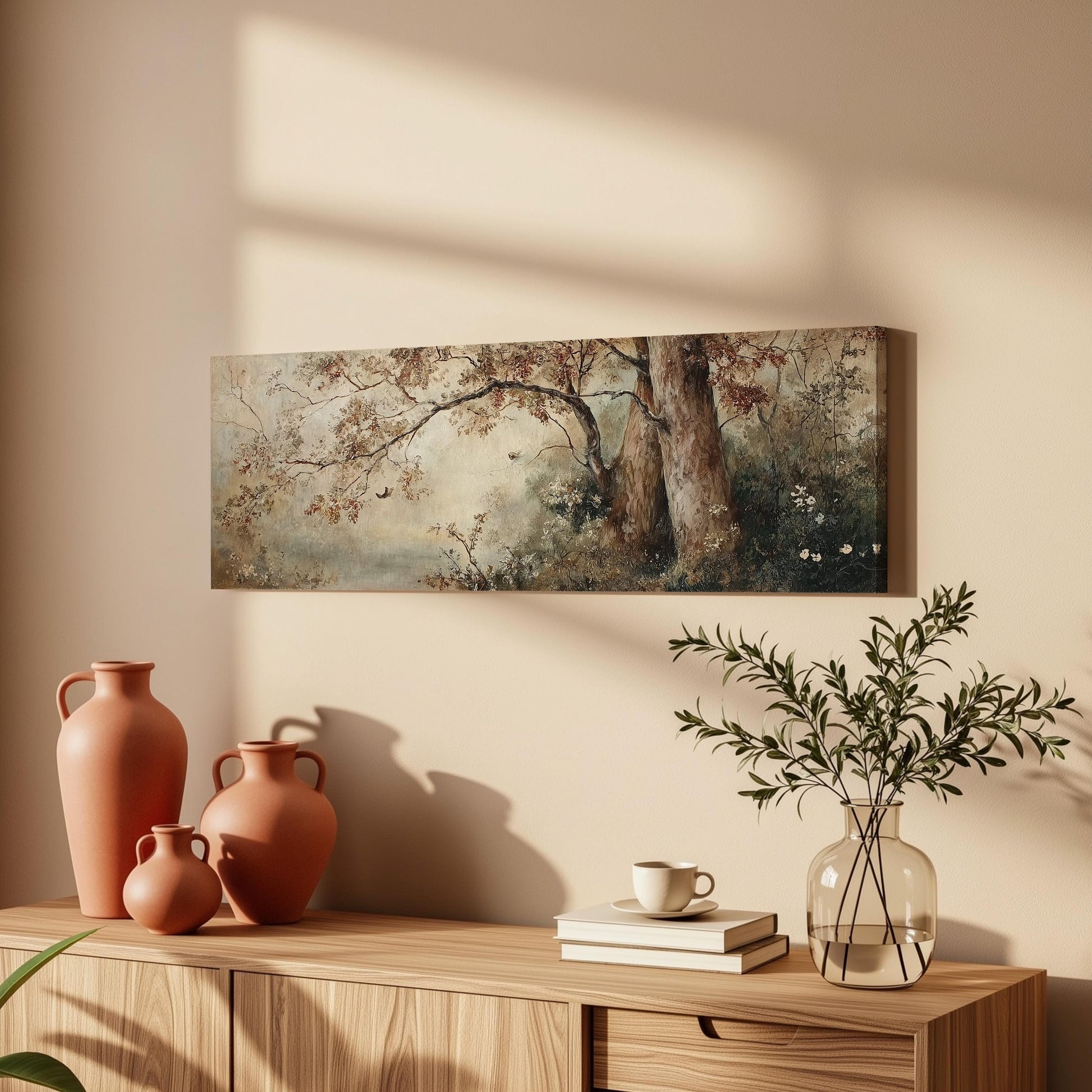 a wooden cabinet with a painting of a tree and flowers hanging on the wall above it. The cabinet also has three orange vases and a glass vase with greenery on top of it.