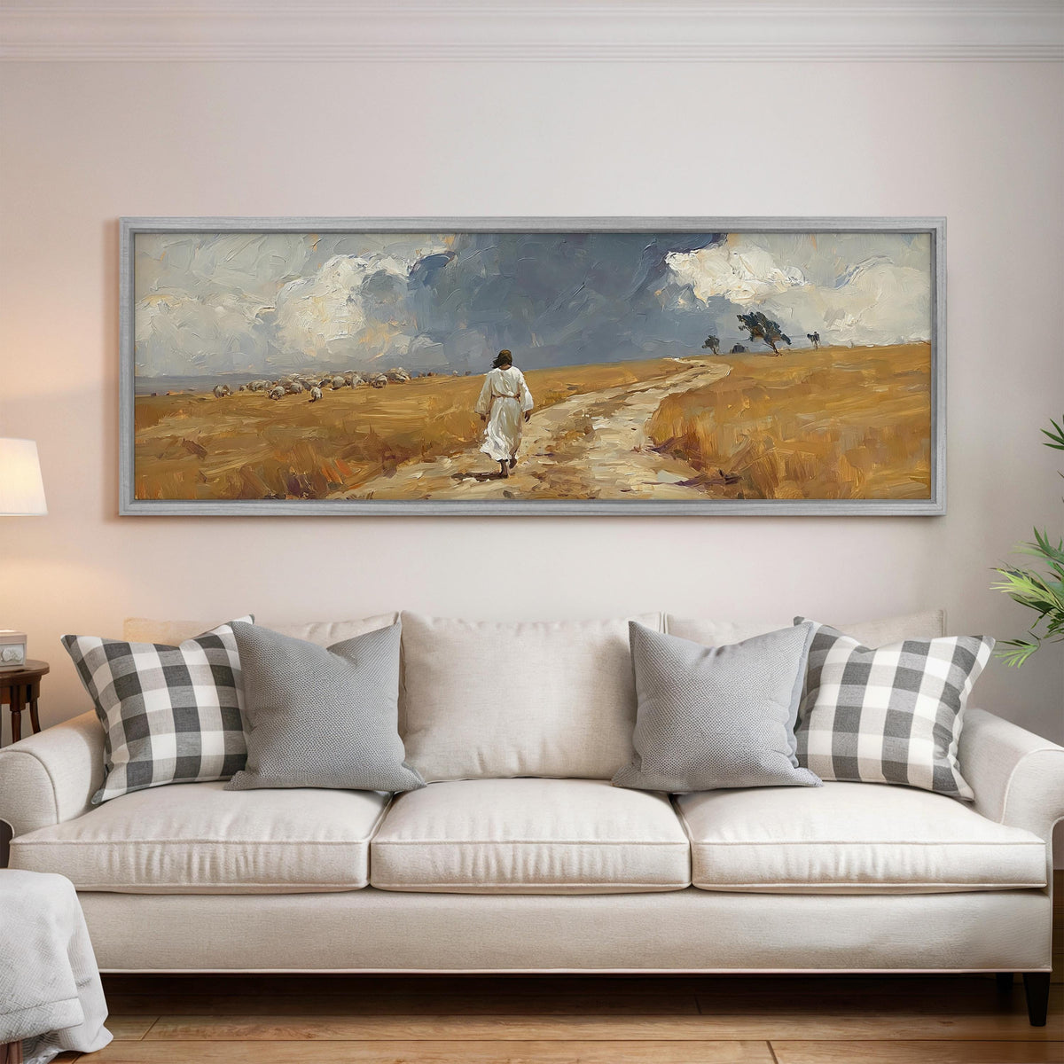 Jesus walking a field path with grazing sheep panoramic canvas print above a white sofa in a bright living room