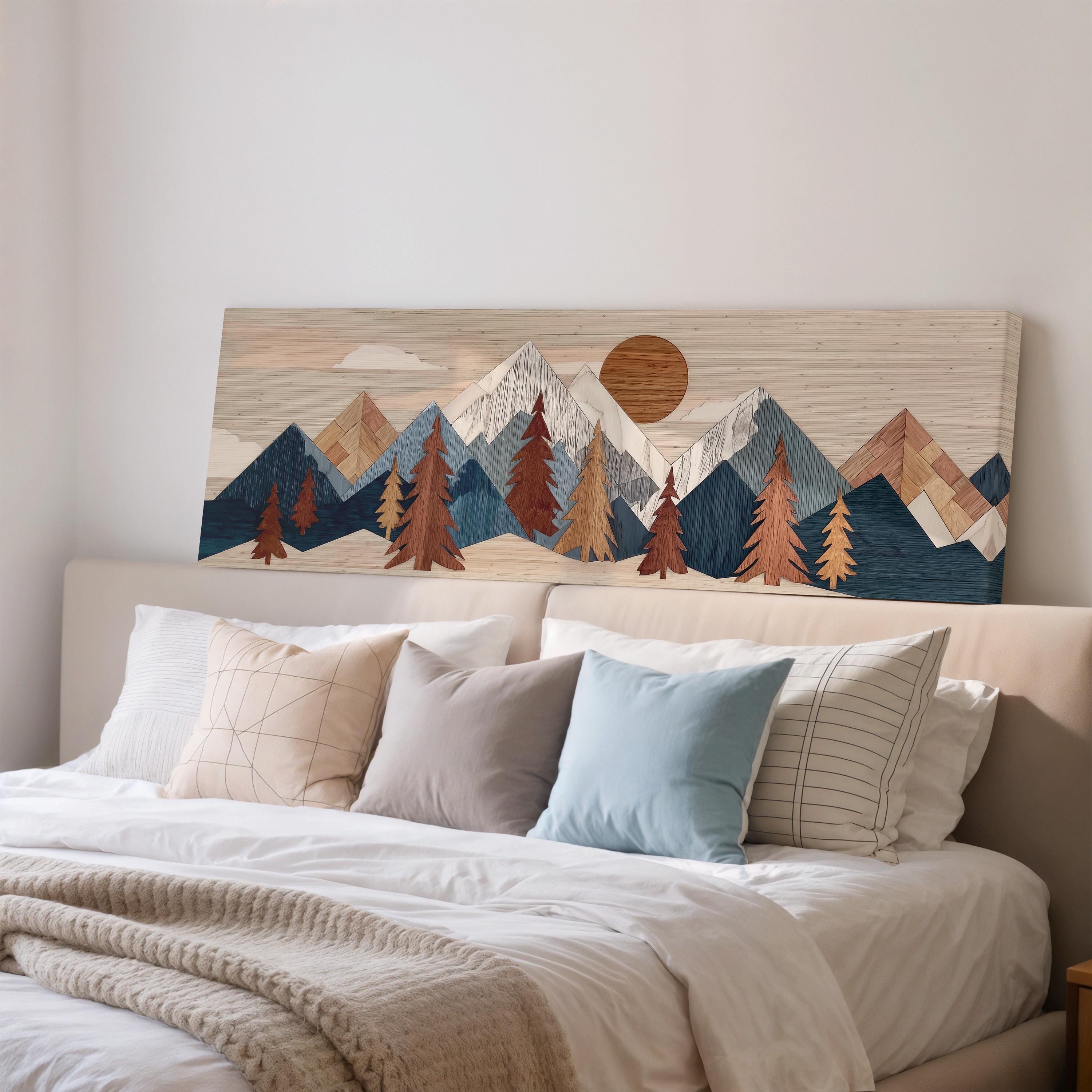 a large wooden landscape artwork hanging on a wall above a bed with white pillows and a gray blanket.