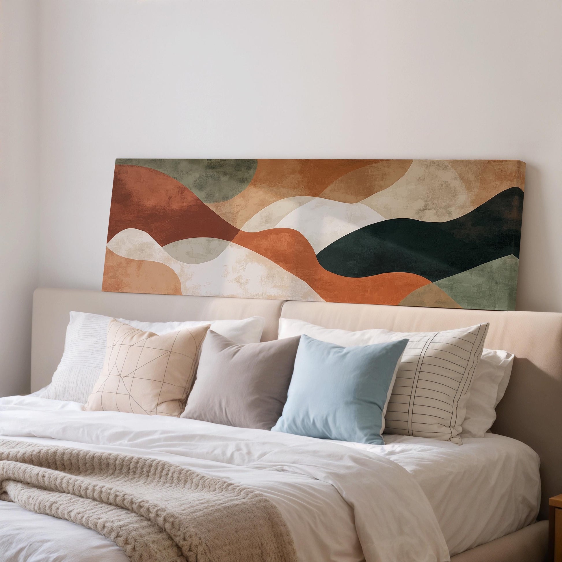 a cozy bedroom scene with a large bed adorned with a white comforter and an assortment of colorful pillows. Above the bed, there is a large abstract painting in shades of orange, green, and brown, adding a unique artistic touch to the room.