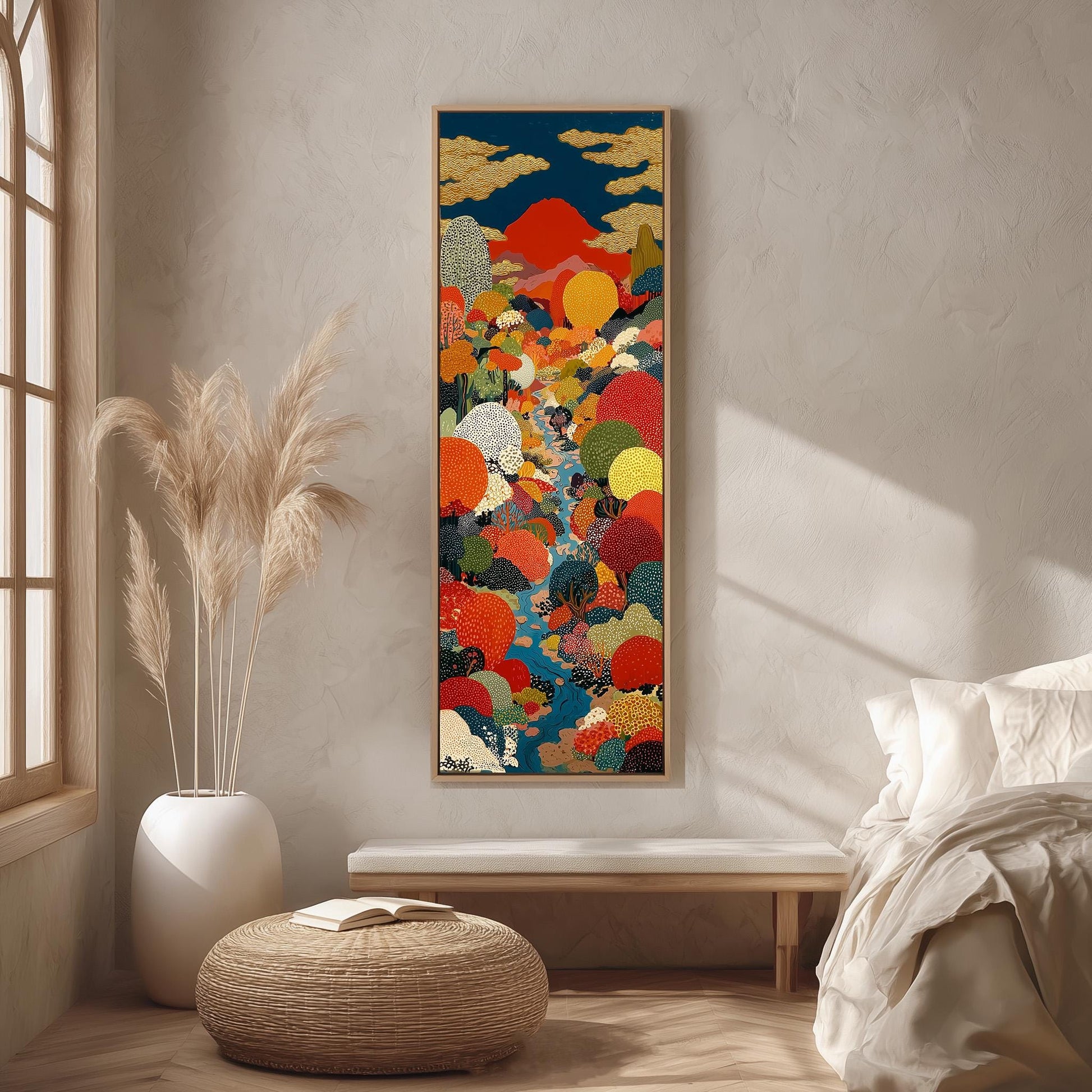 a large, colorful painting hanging on a wall in a room with a bed, a wicker ottoman, and a potted plant.