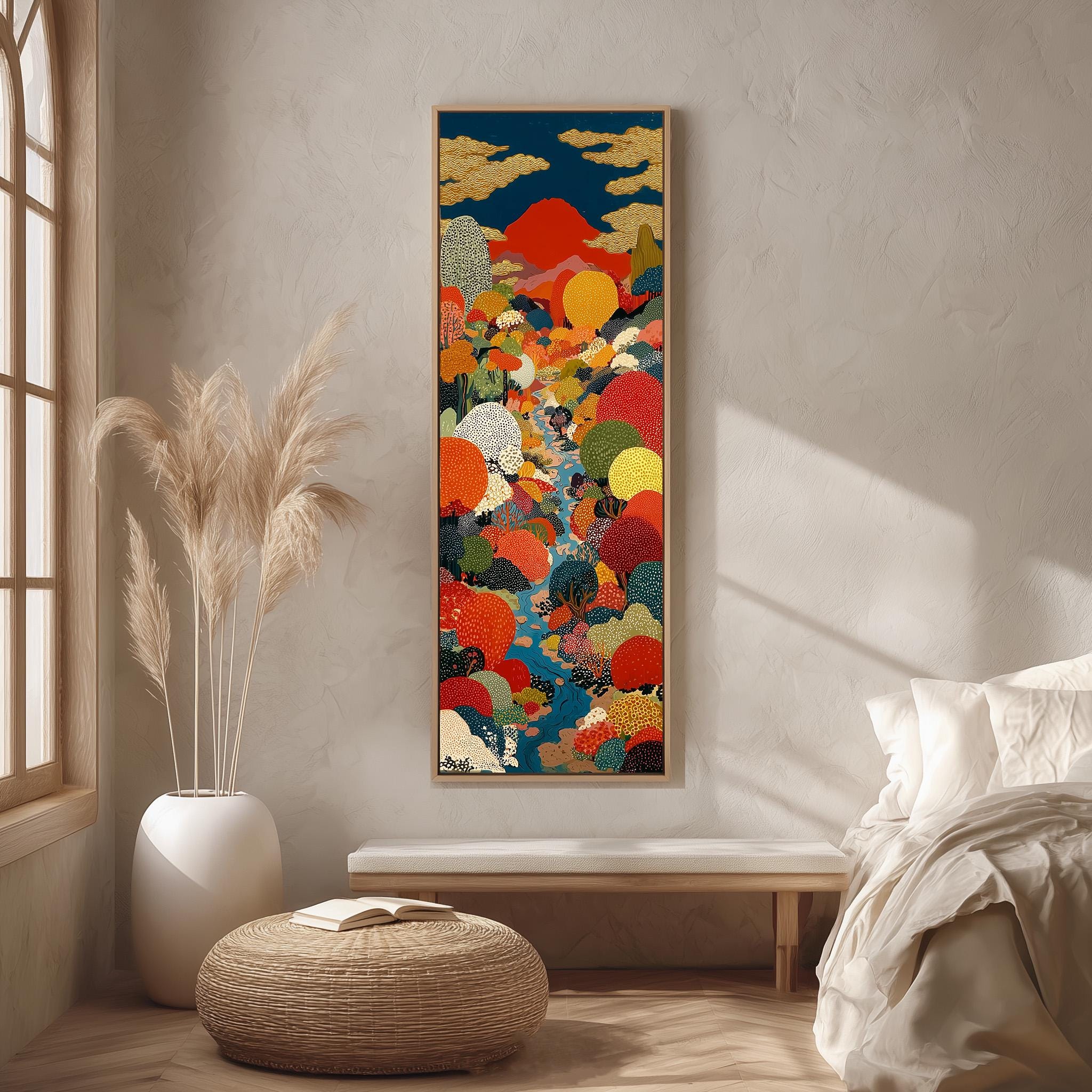 a large, colorful painting hanging on a wall in a room with a bed, a wicker ottoman, and a potted plant.