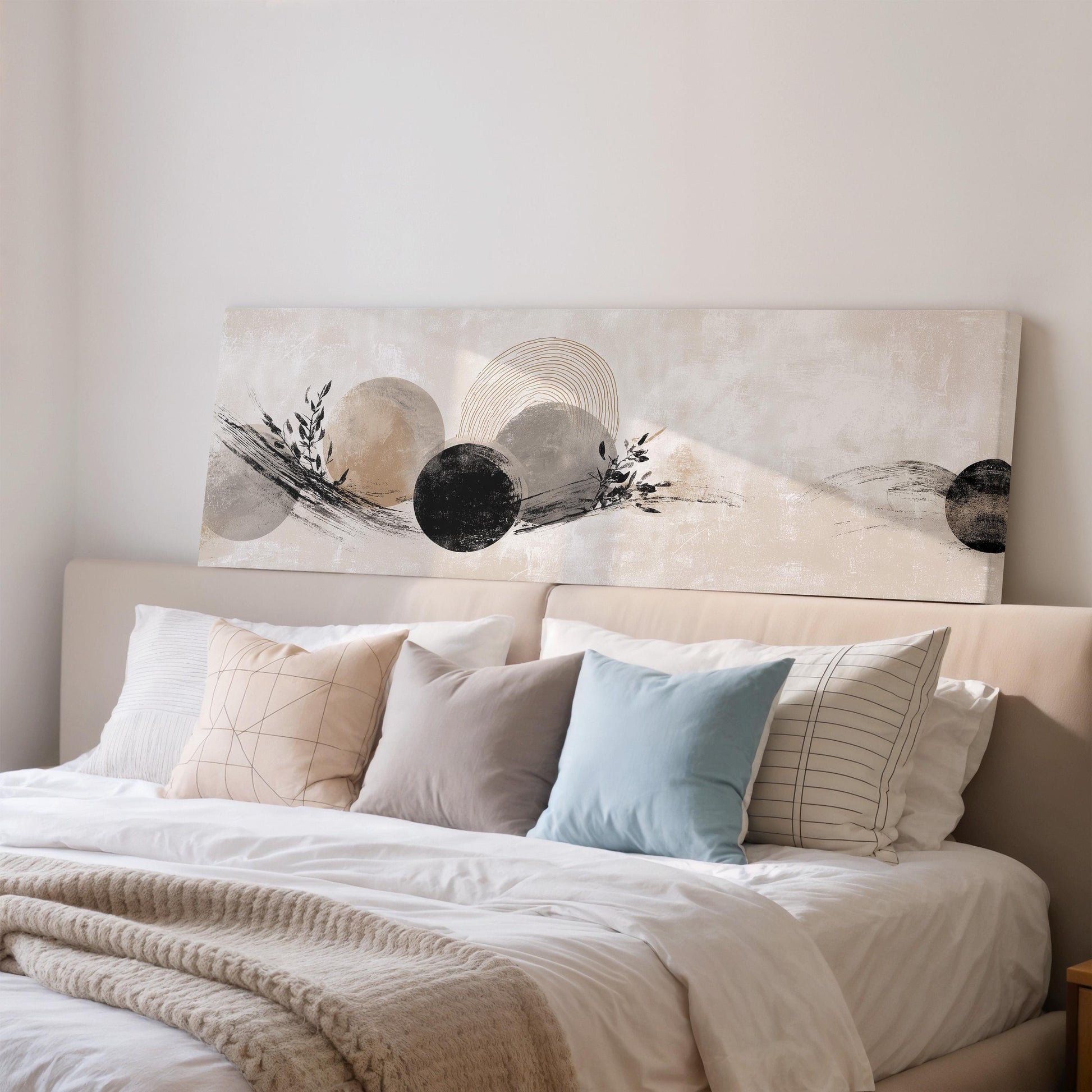a well-made bed with a white comforter and various pillows in different colors and patterns. Above the bed, there is a large abstract painting or artwork on the wall.