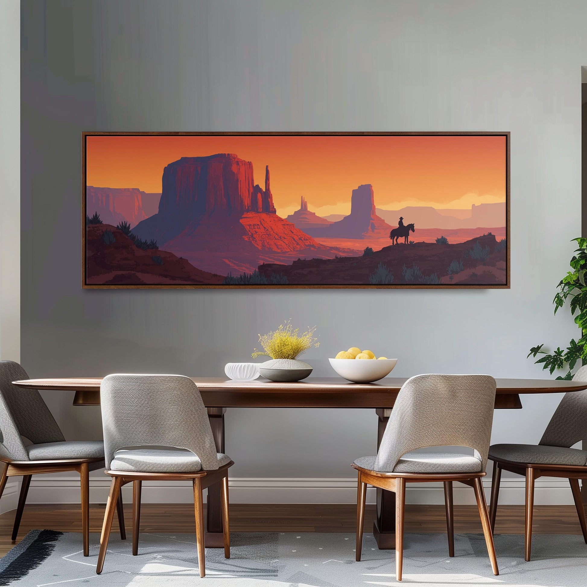 a large framed painting of a desert landscape with mountains and a cowboy on horseback, hanging on a wall above a wooden dining table with four chairs.