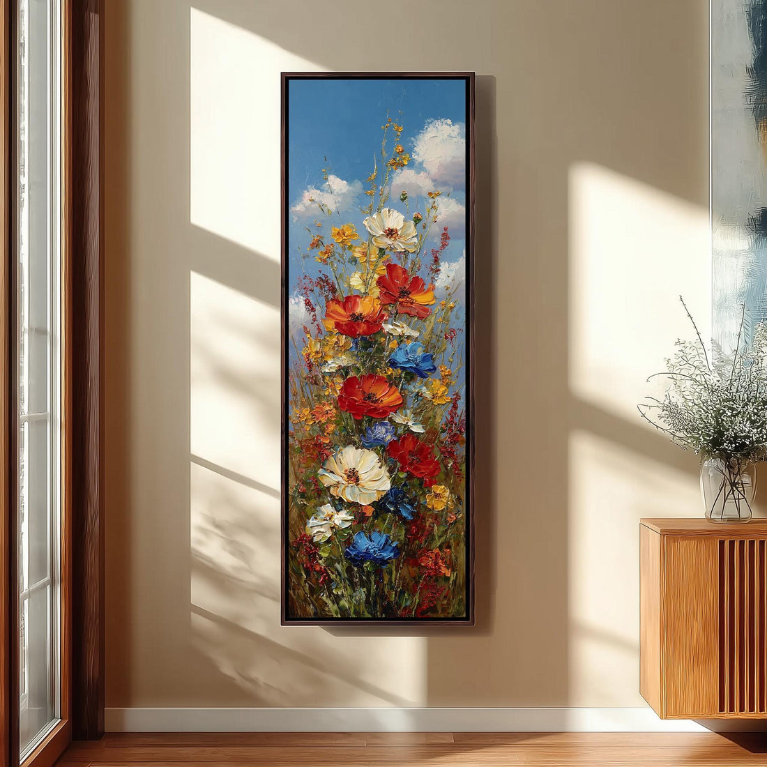 a large, colorful painting of a flower arrangement hanging on a wall in a room with a wooden cabinet below it.
