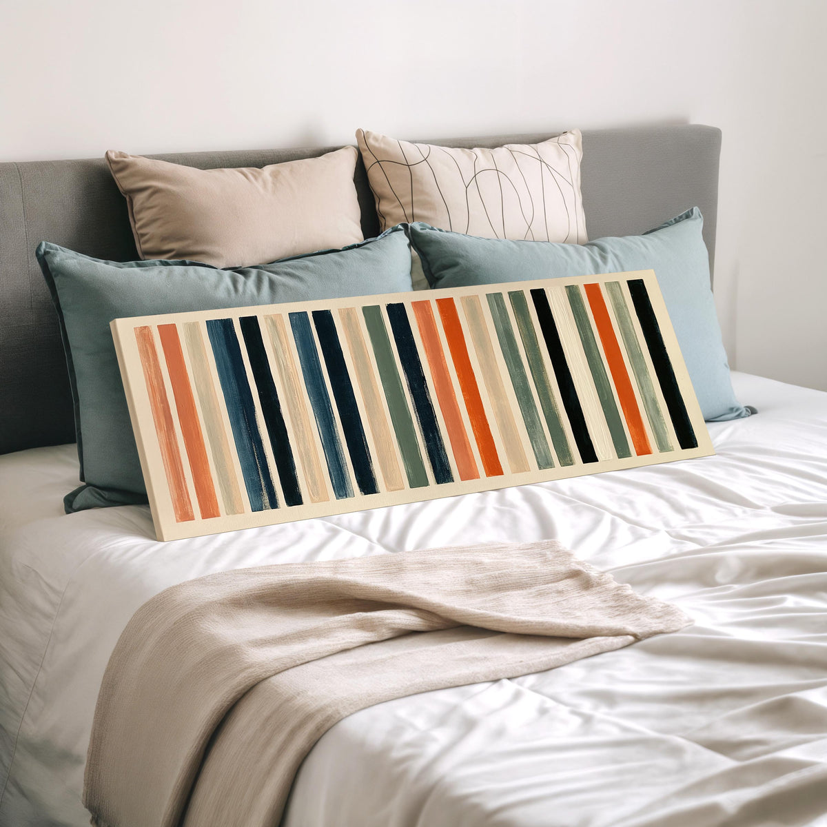 Bold peach, sage and navy stripes wide panoramic canvas print laid on a bed to show its size