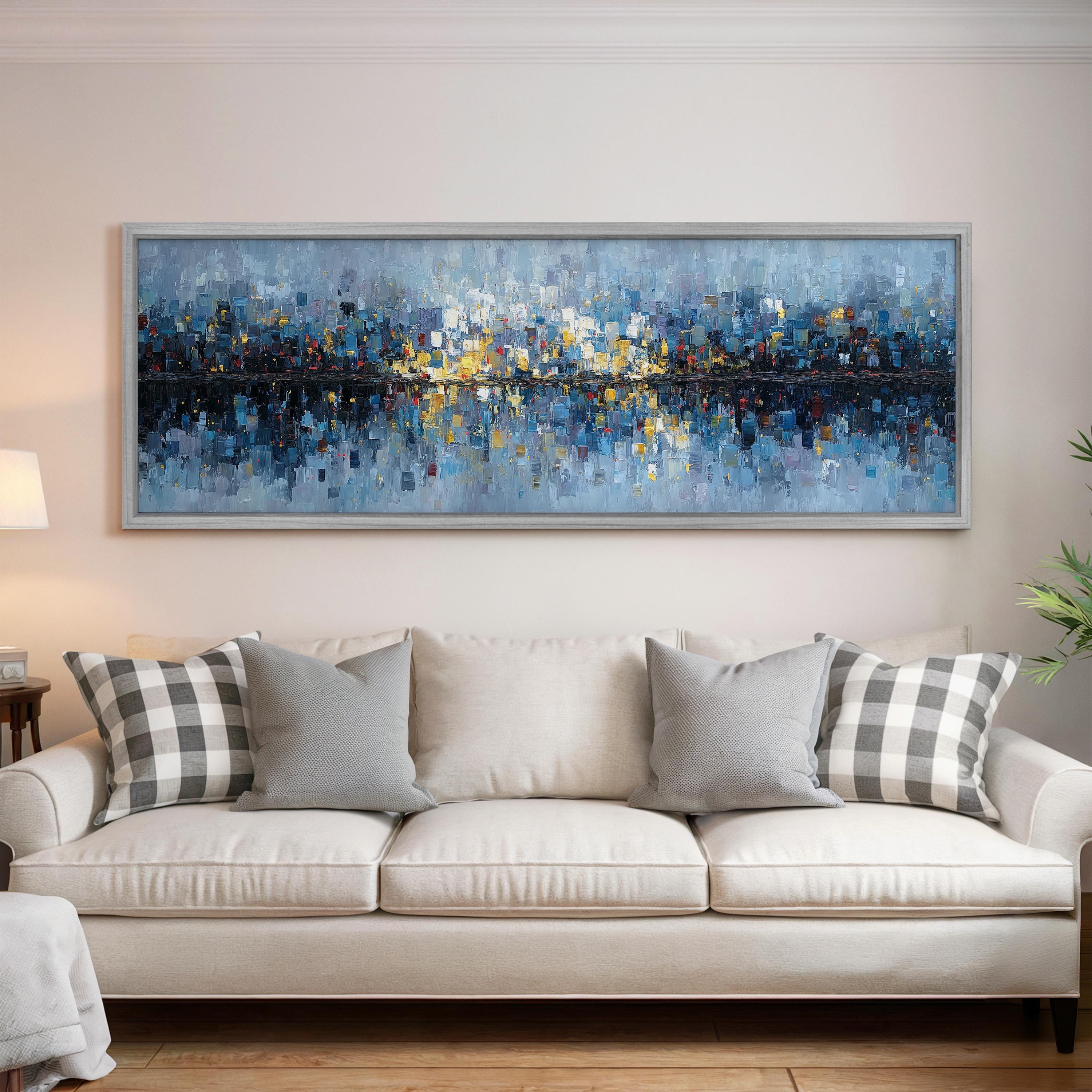 a large, colorful painting of a cityscape hanging on a wall above a white couch with gray and white patterned pillows.