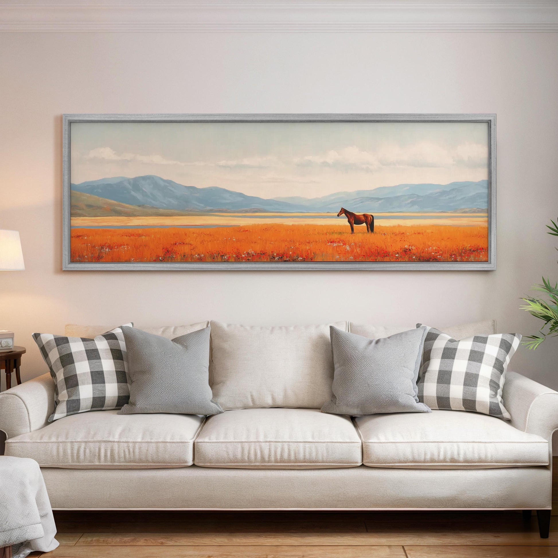 a large painting of a horse in a field, hanging on a wall above a white couch with gray and white plaid throw pillows.