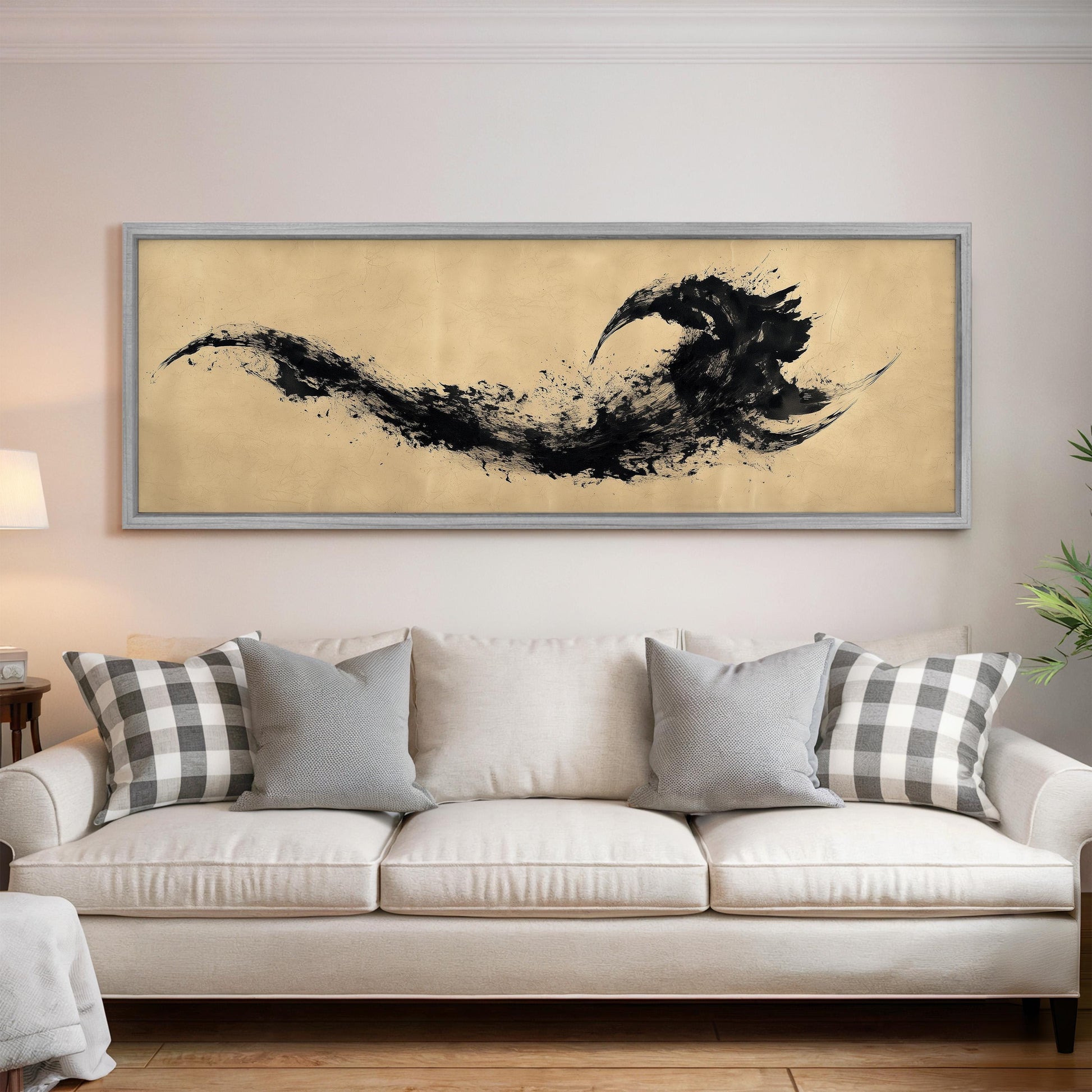 a large, framed artwork hanging on a wall above a white couch with gray and white plaid throw pillows.