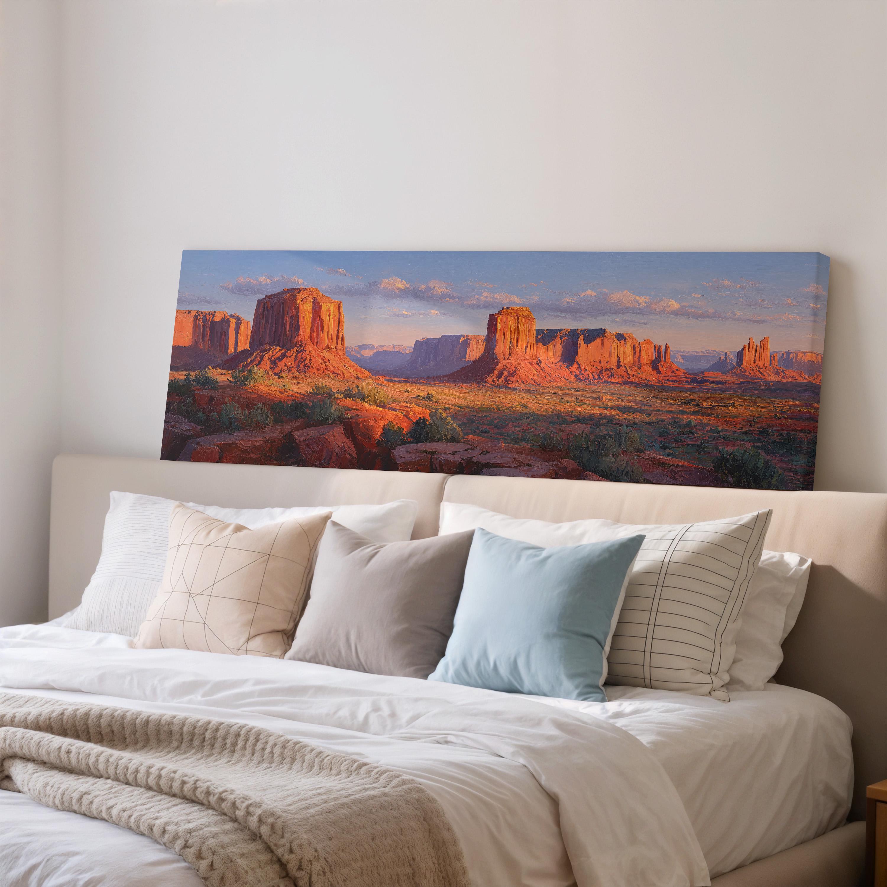 a large, framed print of a desert landscape with mountains in the background, hanging on a wall above a bed with white bedding and pillows.