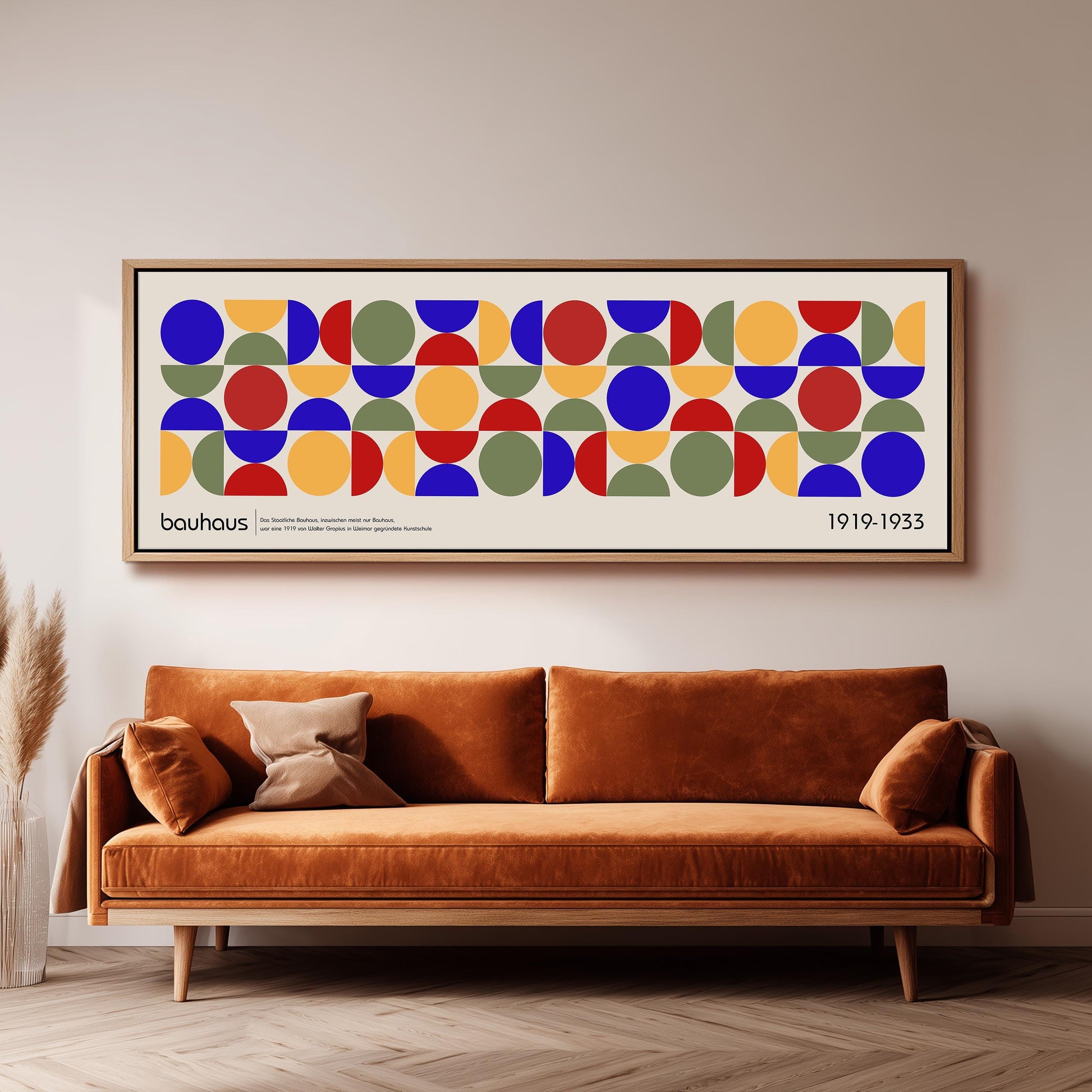 a large abstract art piece with a geometric pattern of circles and rectangles on a white background, hanging on a wall above a brown sofa.