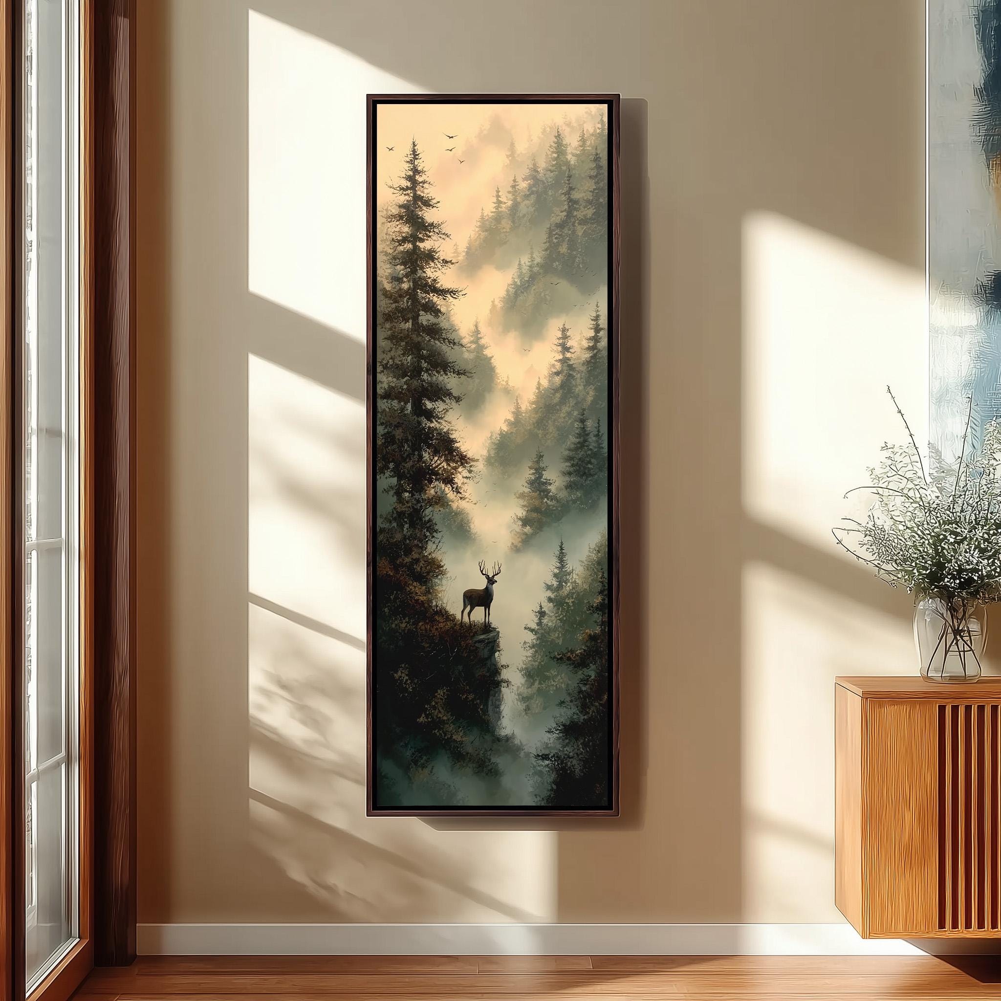 a large framed painting of a forest scene with a deer standing on a cliff overlooking the misty landscape.