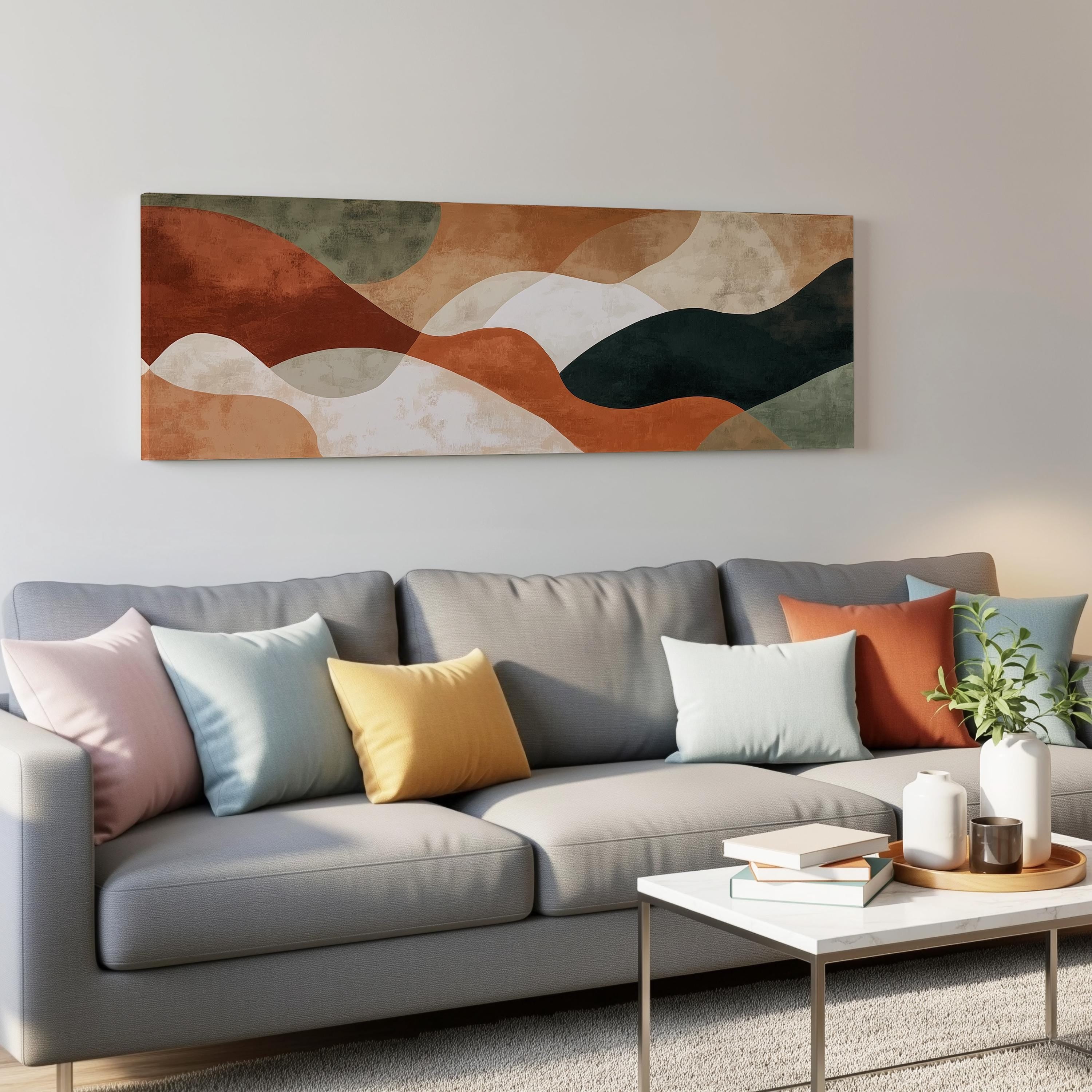 a modern living room with a gray sofa adorned with colorful throw pillows. Above the sofa, there is a large abstract painting hanging on the wall. In front of the sofa, there is a white coffee table with a stack of books and a small plant.