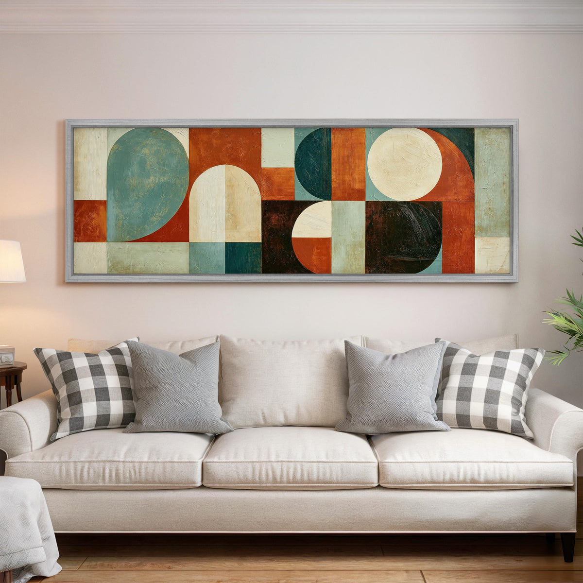 Teal and rust arch and circle shapes panoramic canvas print above a white sofa in a bright living room