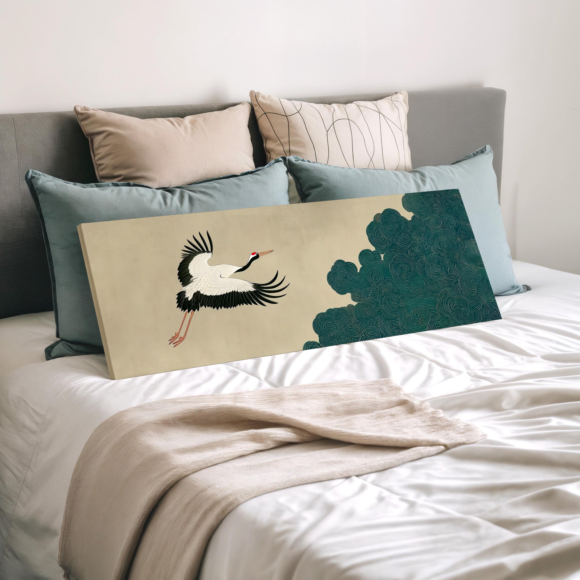 a large bed with a white comforter and a painting of a crane on it. The bed is surrounded by various pillows and a blanket.