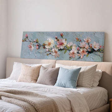 a large painting of flowers on a wall above a bed with white pillows and a gray blanket.