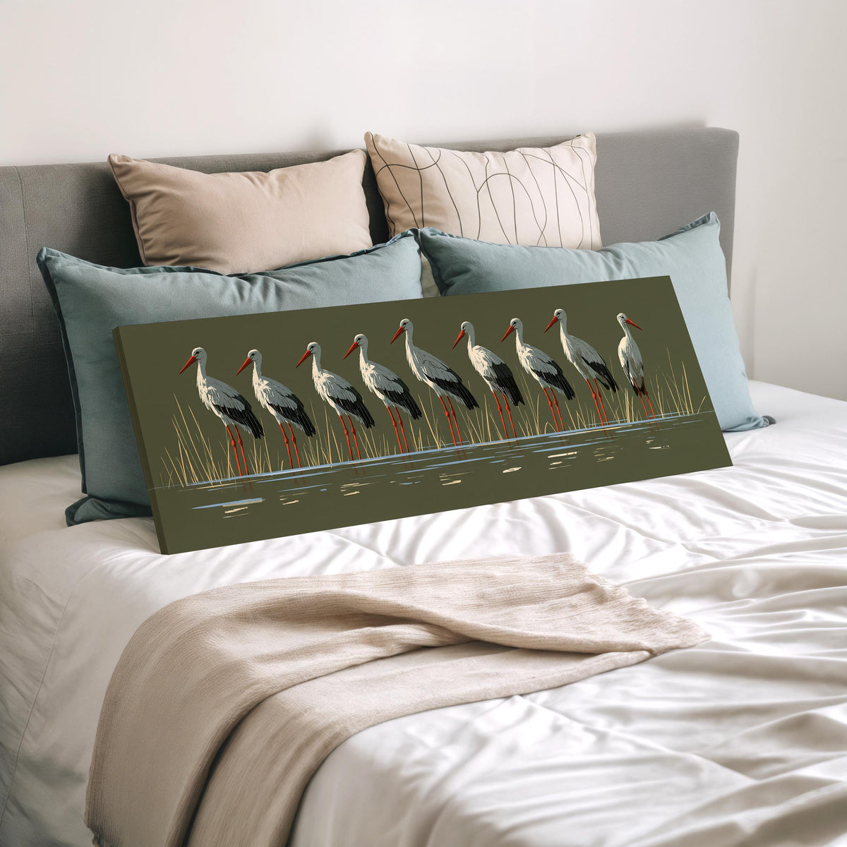 Flock of storks on olive green wide panoramic canvas print laid on a bed to show its size