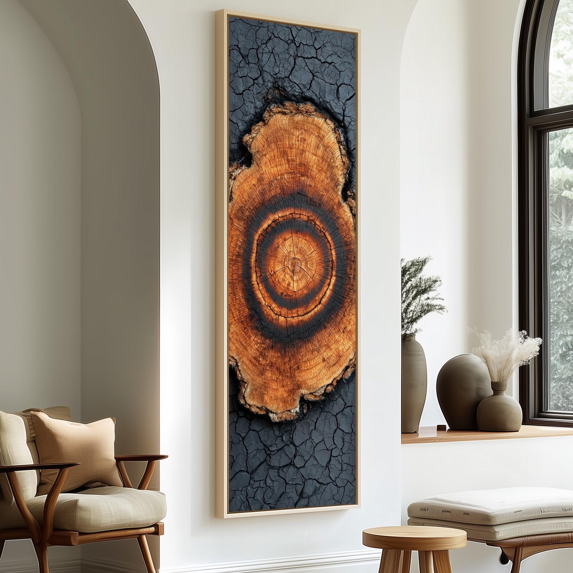 a large framed artwork depicting a tree stump with a circular pattern on it, hanging on a white wall in a room with a wooden chair and a small table.