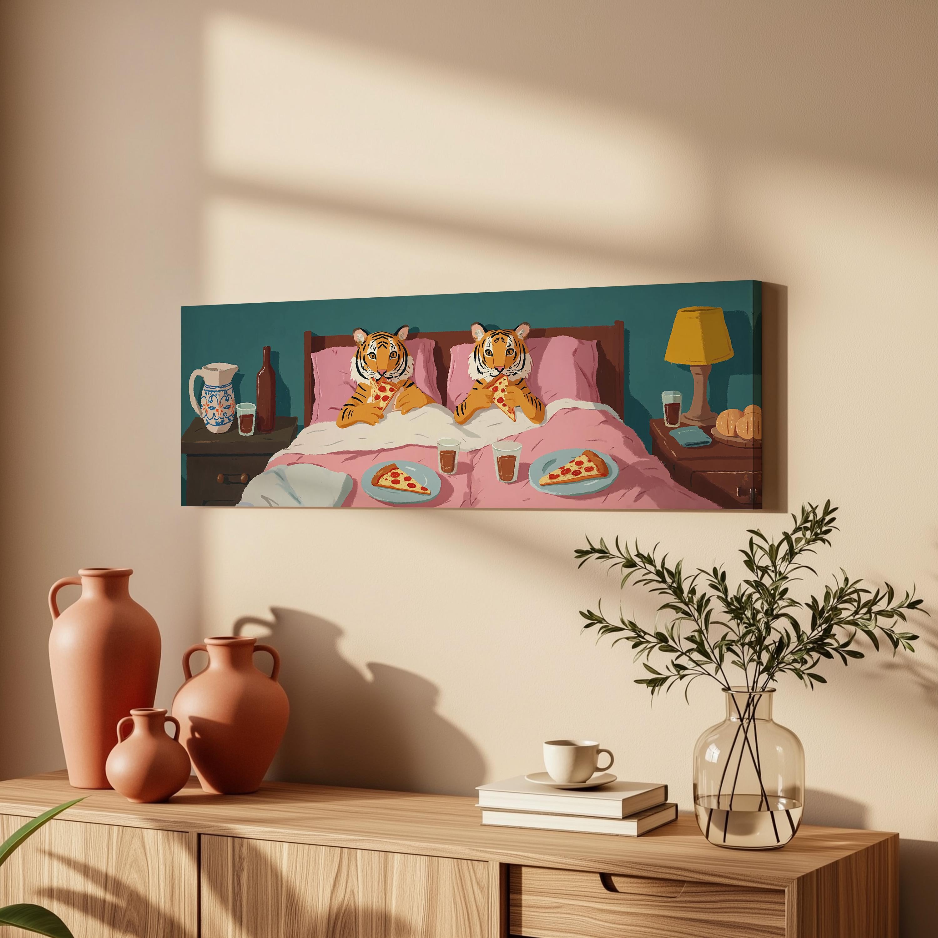 a painting of two tiger characters lying in bed, with plates of pizza and drinks on the bed. The painting is hanging on a wall above a wooden dresser, which has a vase, a plant, and some books on it.