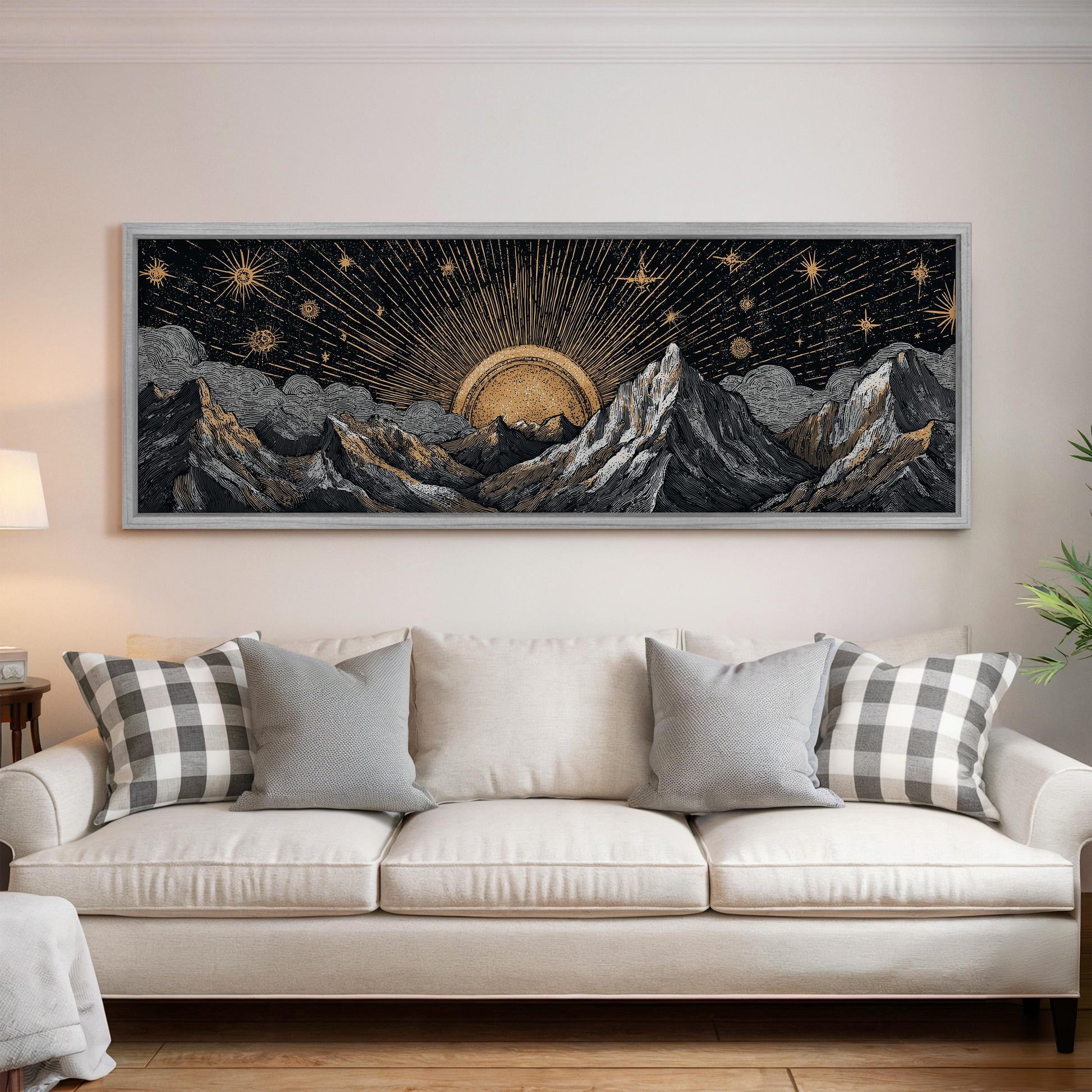 a large framed artwork depicting a night sky with mountains and a sun in the center, hanging on a wall above a white couch with decorative pillows.